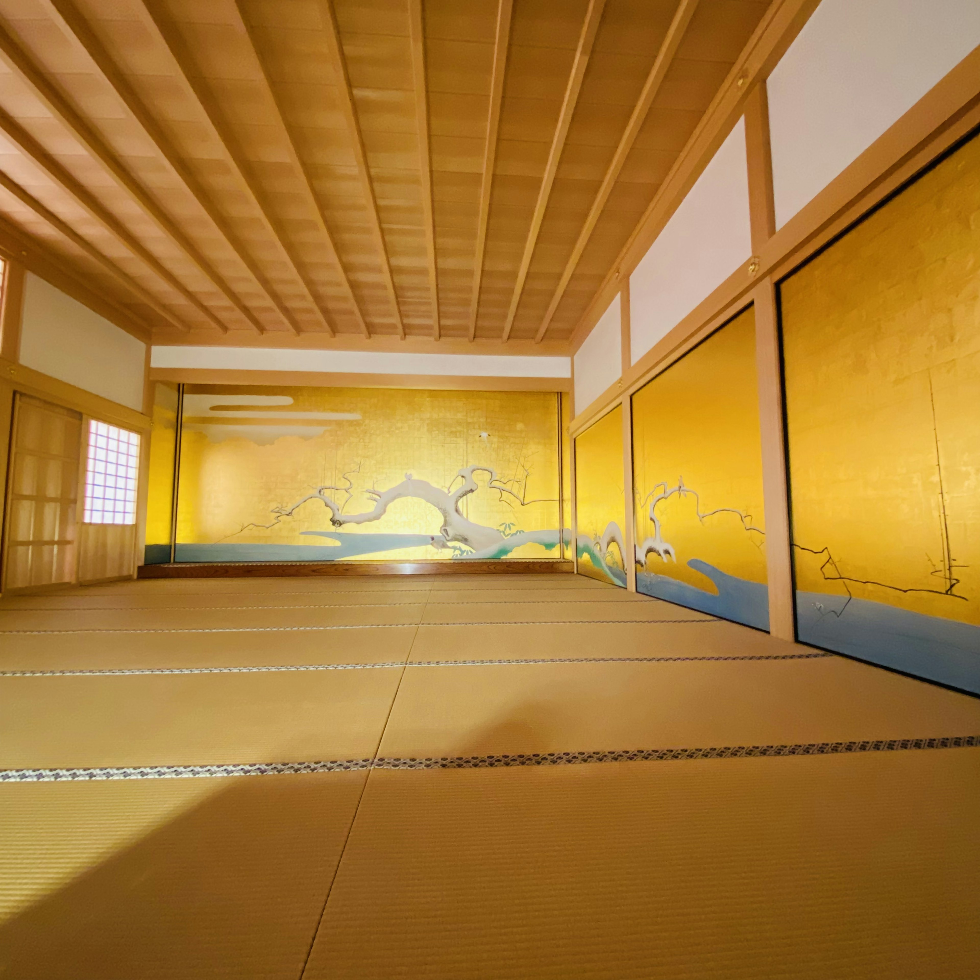 Innenraum eines traditionellen japanischen Zimmers mit gelben Wänden und Holzdecke sowie Tatami-Boden