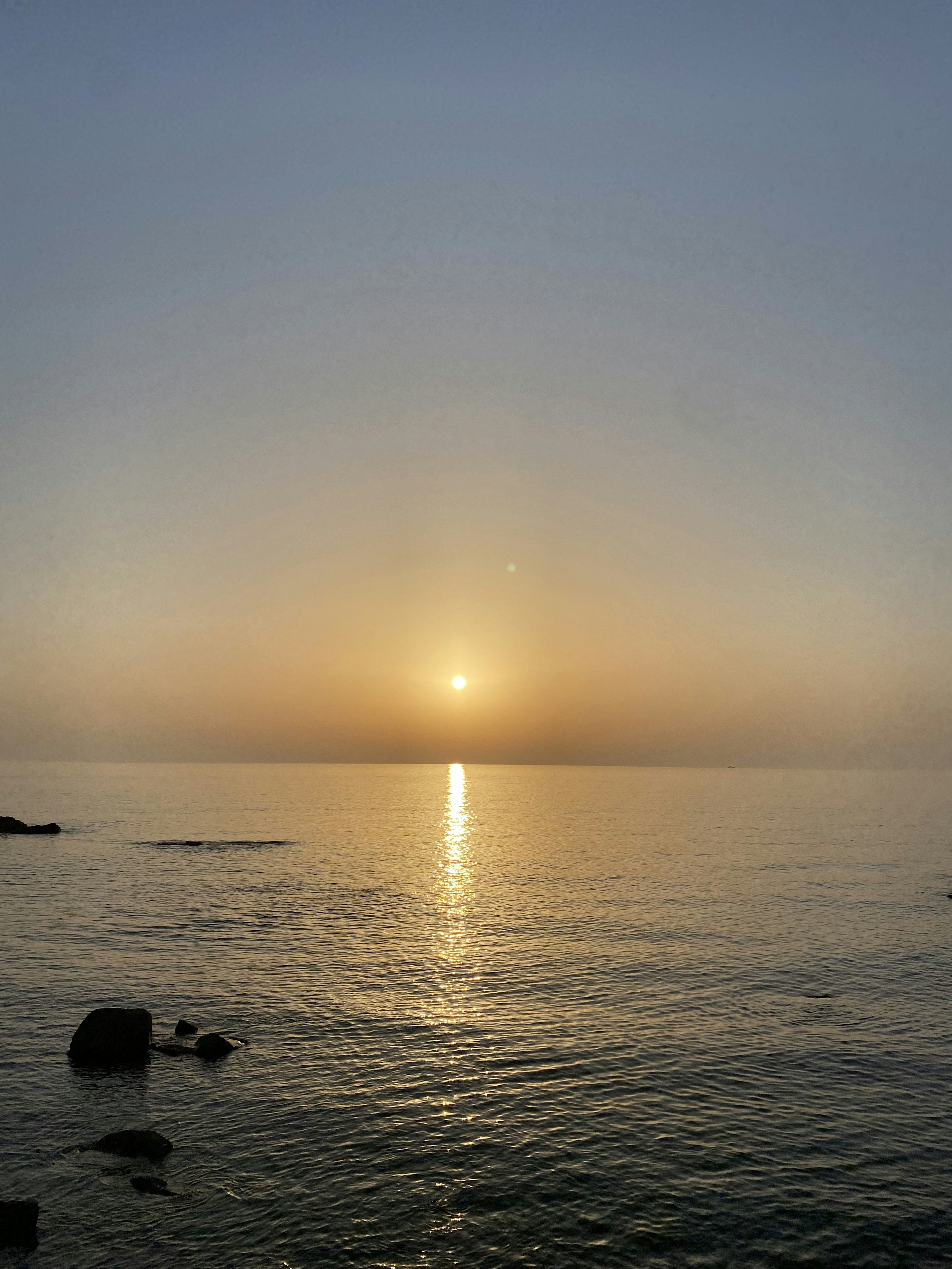 穏やかな海の風景に沈む夕日が映る