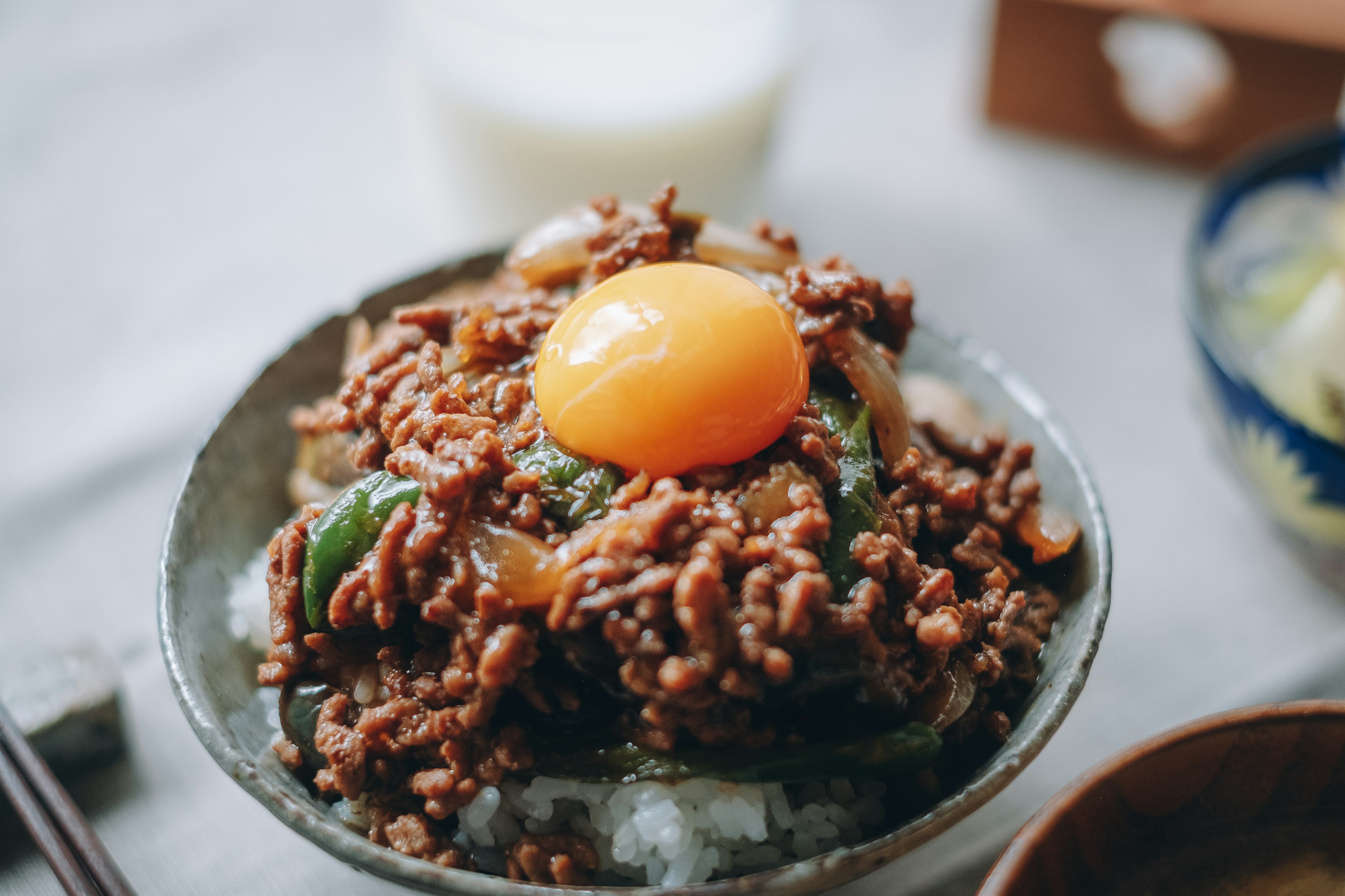 A bowl of rice topped with minced meat and a raw egg