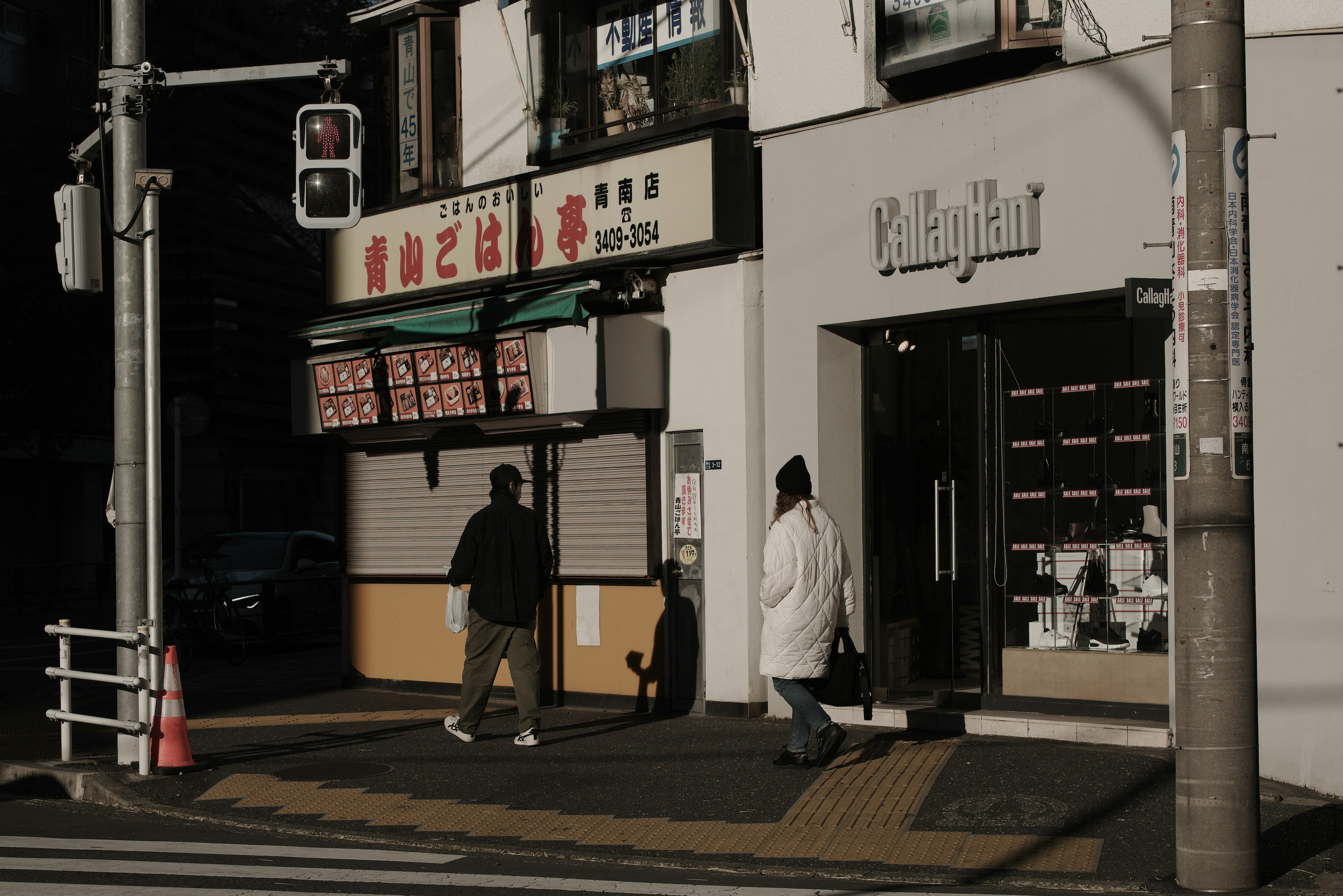 Escena de personas caminando en una esquina oscura de la calle con letreros de tiendas