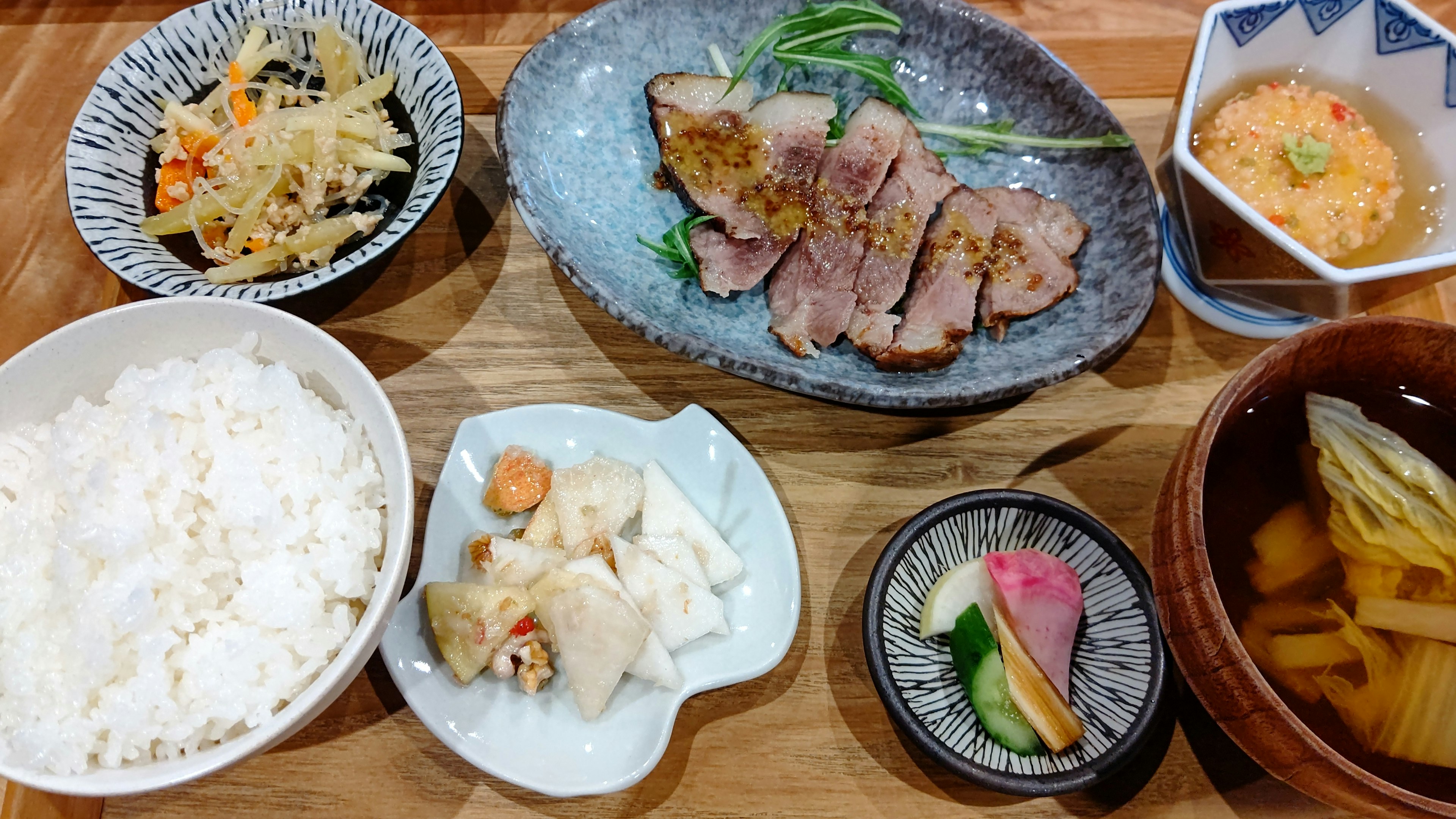 Beautifully arranged Japanese meal featuring rice sliced chicken simmered vegetables and salad