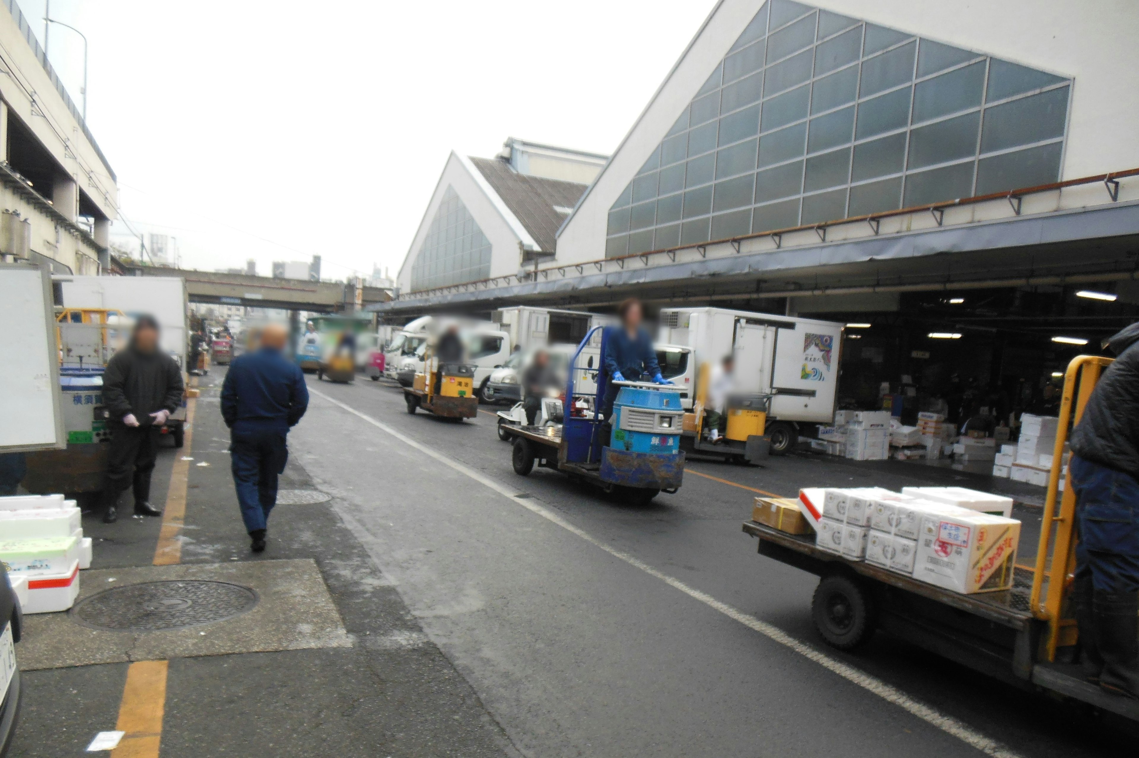 Una strada di mercato affollata con camion e carrelli che trasportano merci