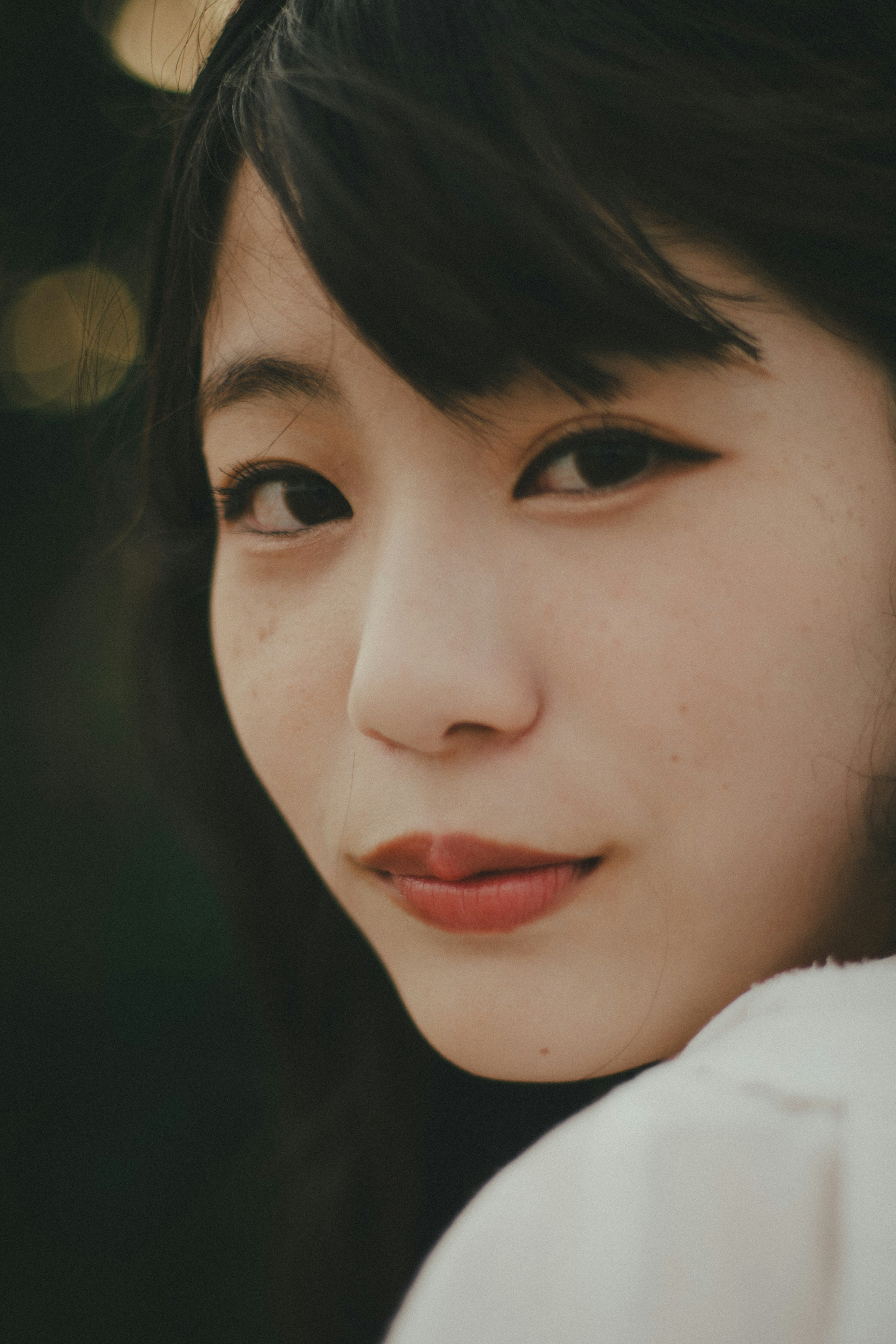 Portrait of a woman with black hair and a natural expression against a soft background