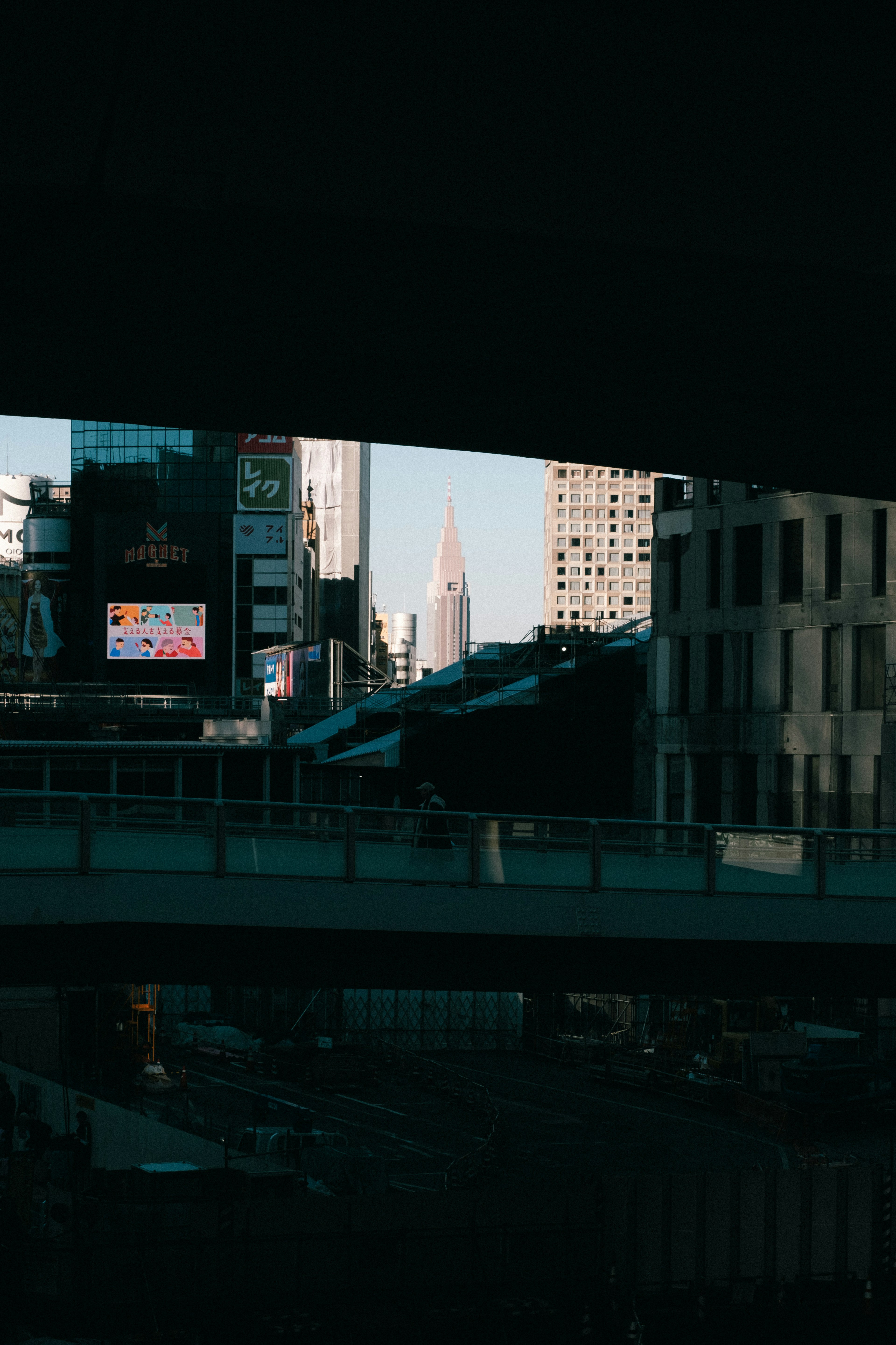 Silhouette des Chrysler Buildings sichtbar durch Hochhäuser und dunkle Überführung