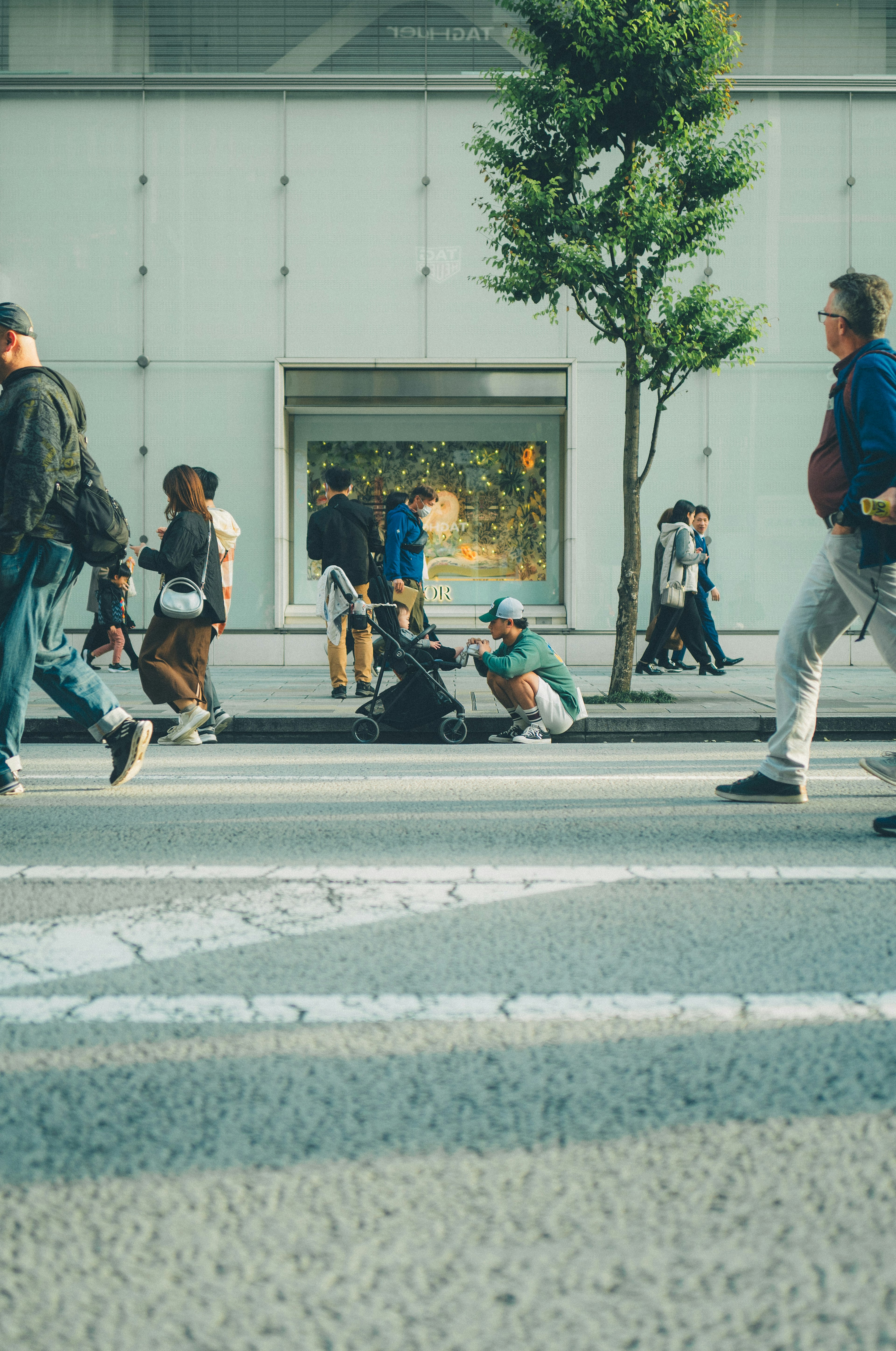 Persone che camminano in un attraversamento pedonale urbano con una vetrina