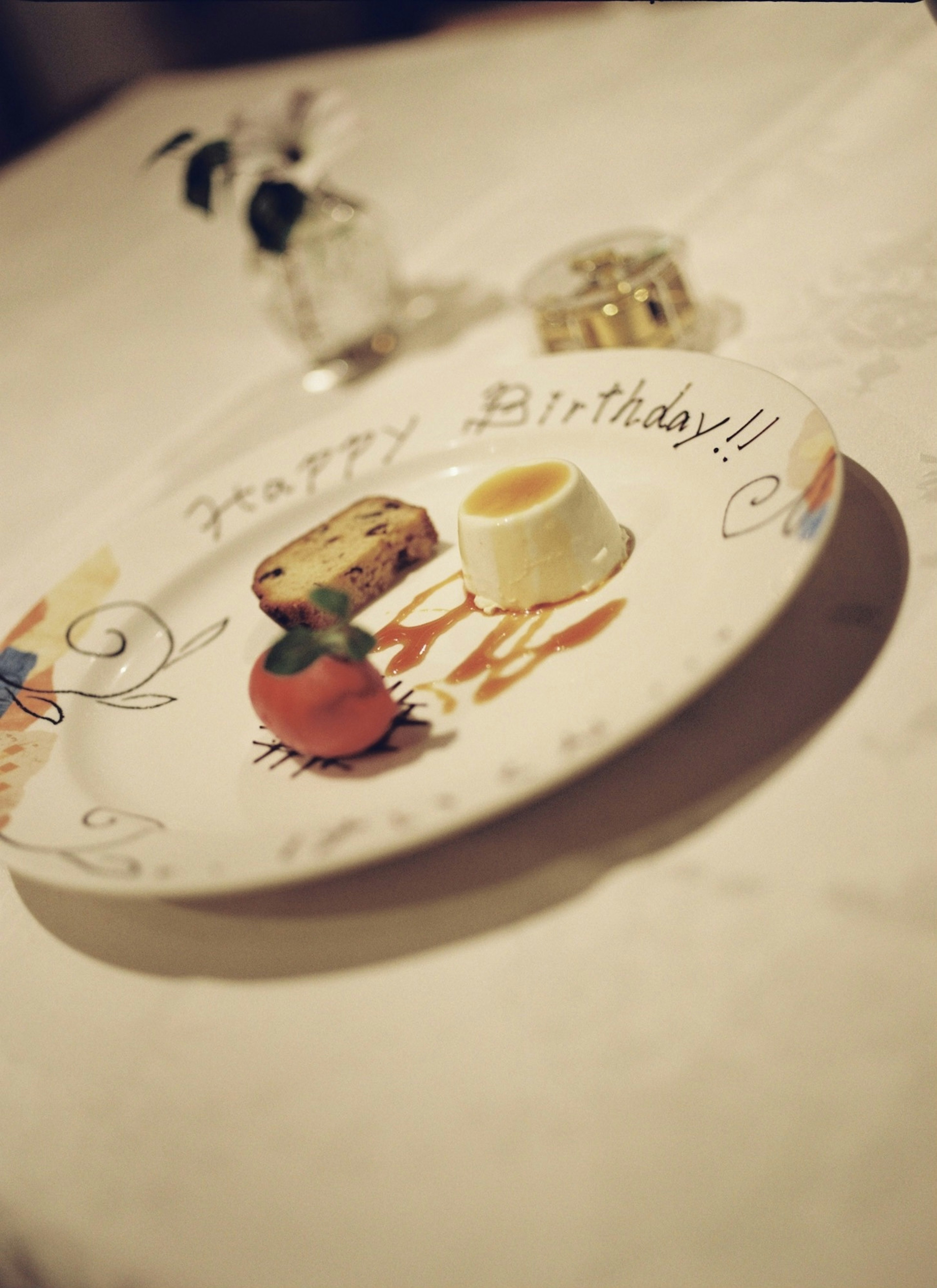 A birthday plate featuring a dessert and fruit with a handwritten message