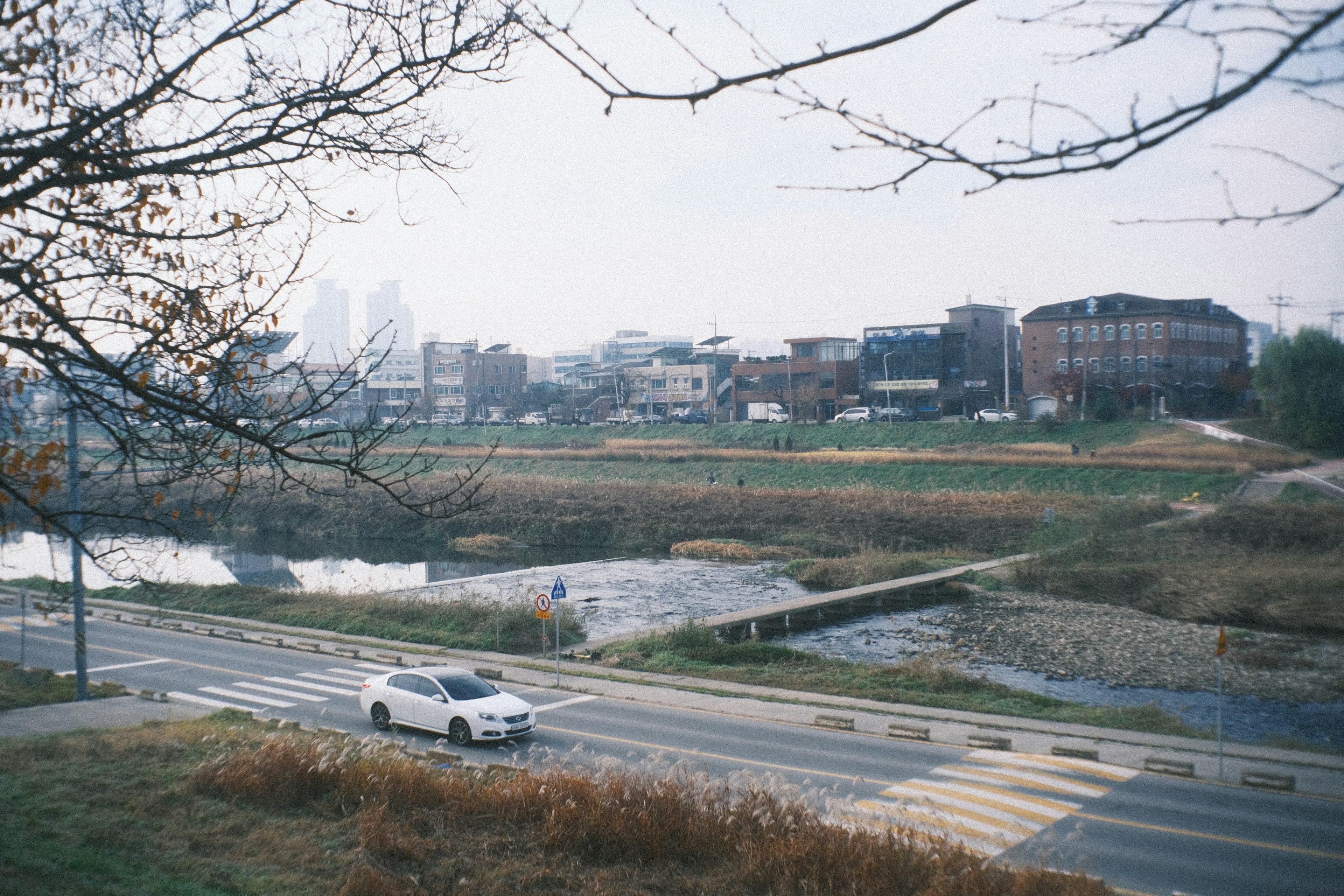 A quiet landscape featuring a road with a passing car and a river