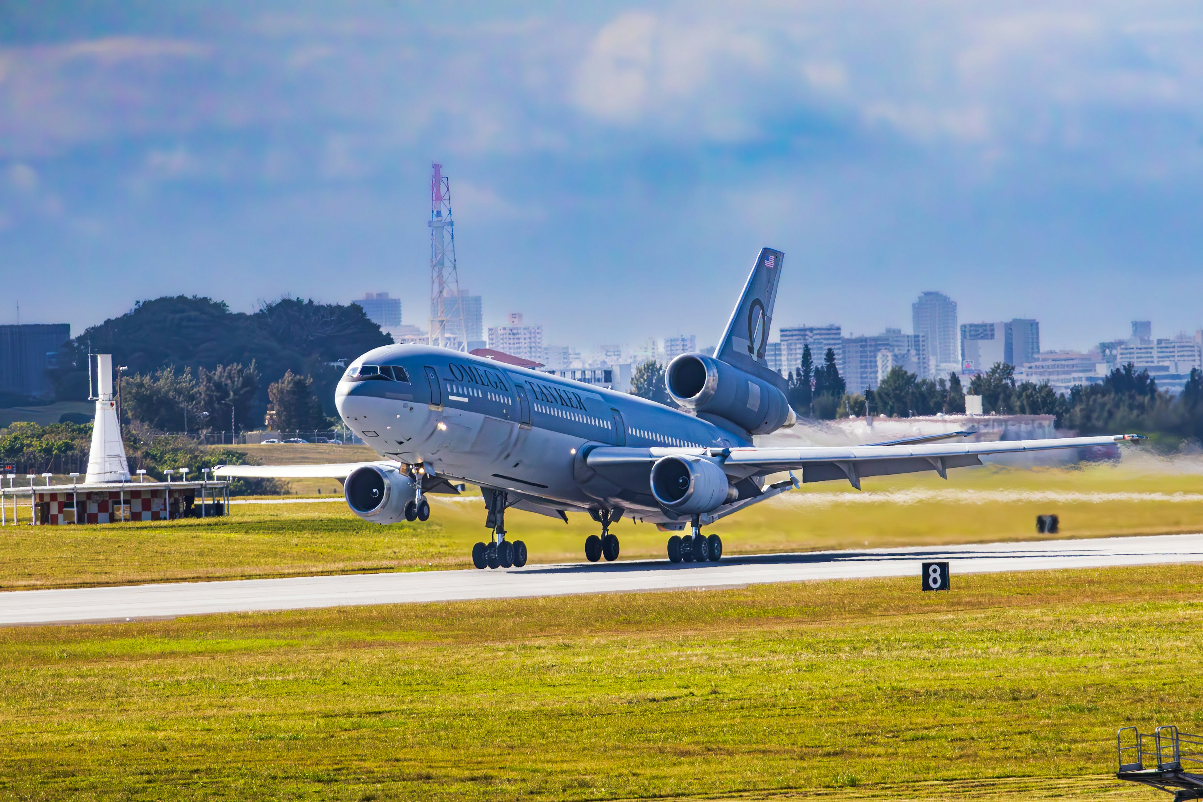 Aircraft taking off from runway with a clear blue sky and city skyline