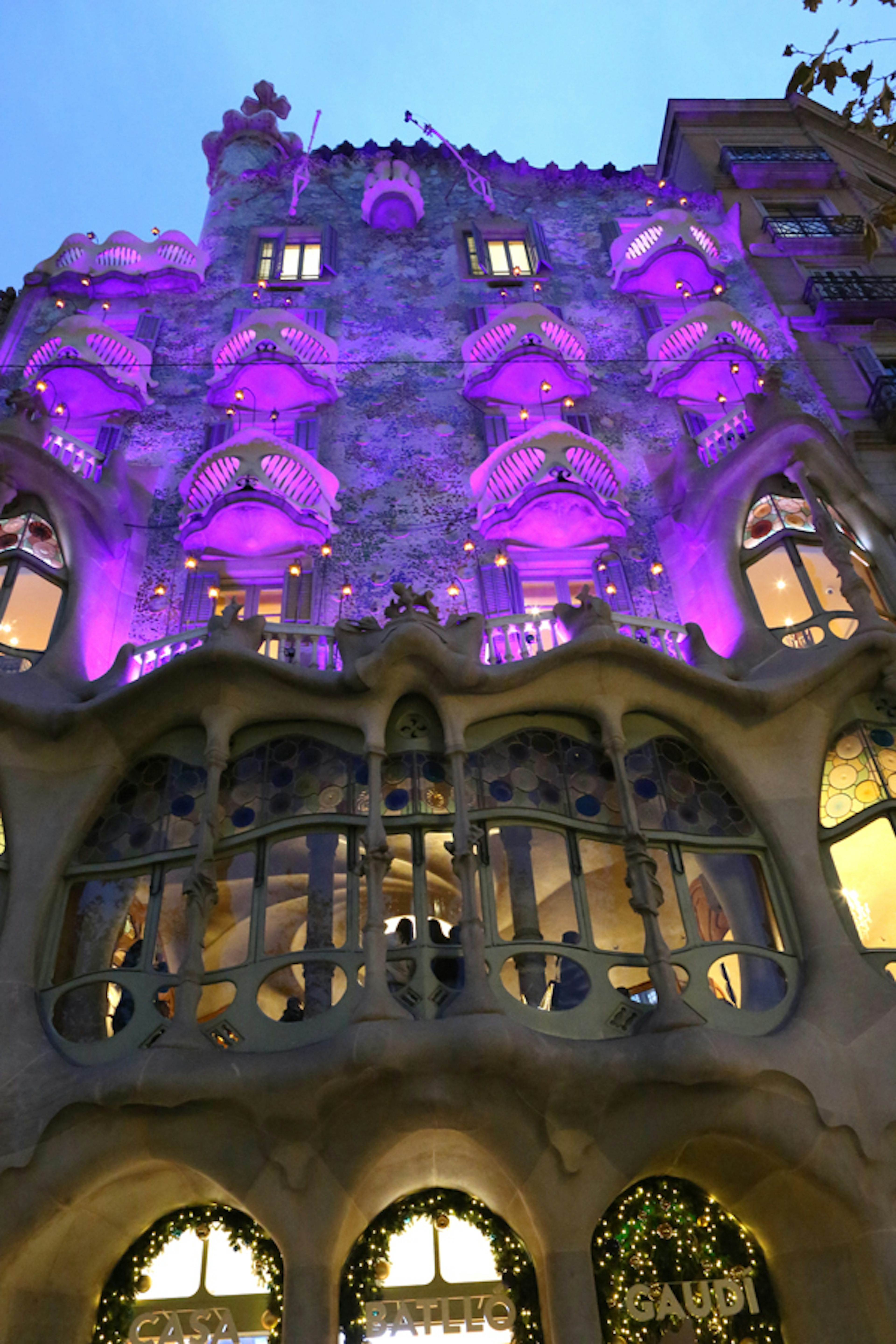 Fachada de la Casa Batlló de Gaudí iluminada en púrpura por la noche