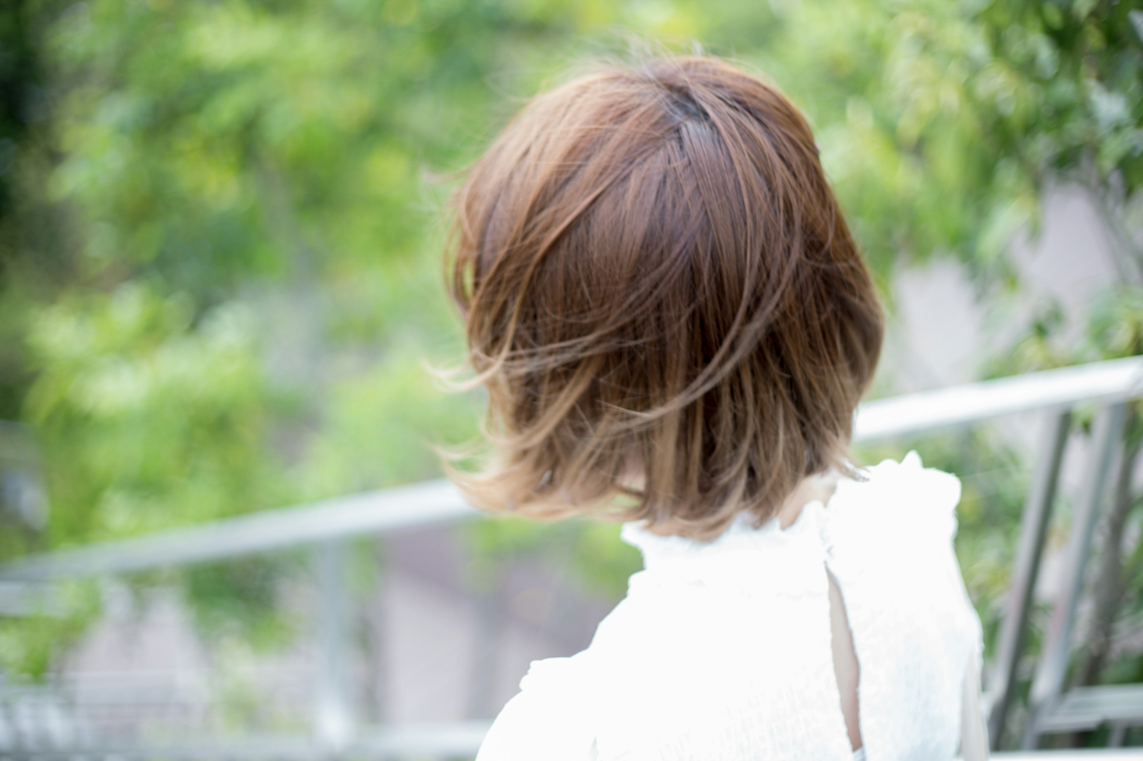 Mujer con cabello corto castaño de espaldas en un fondo verde