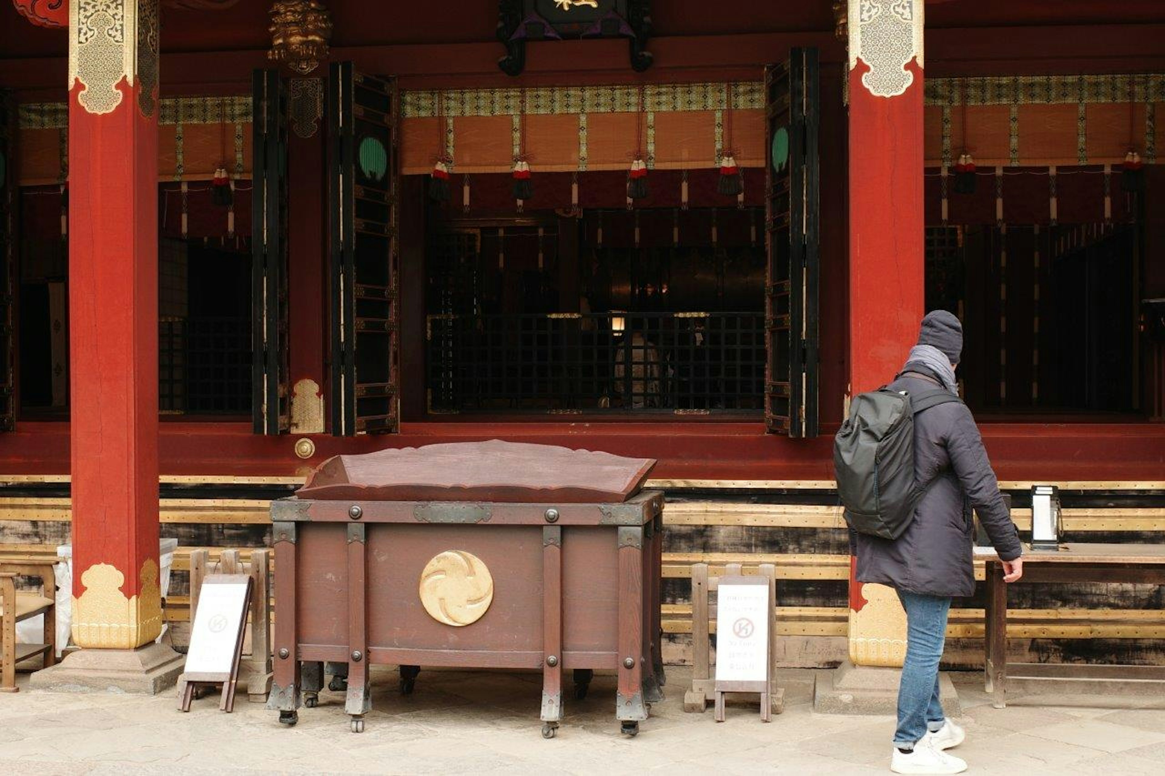 赤い柱のある神社に近づく人と木製の箱