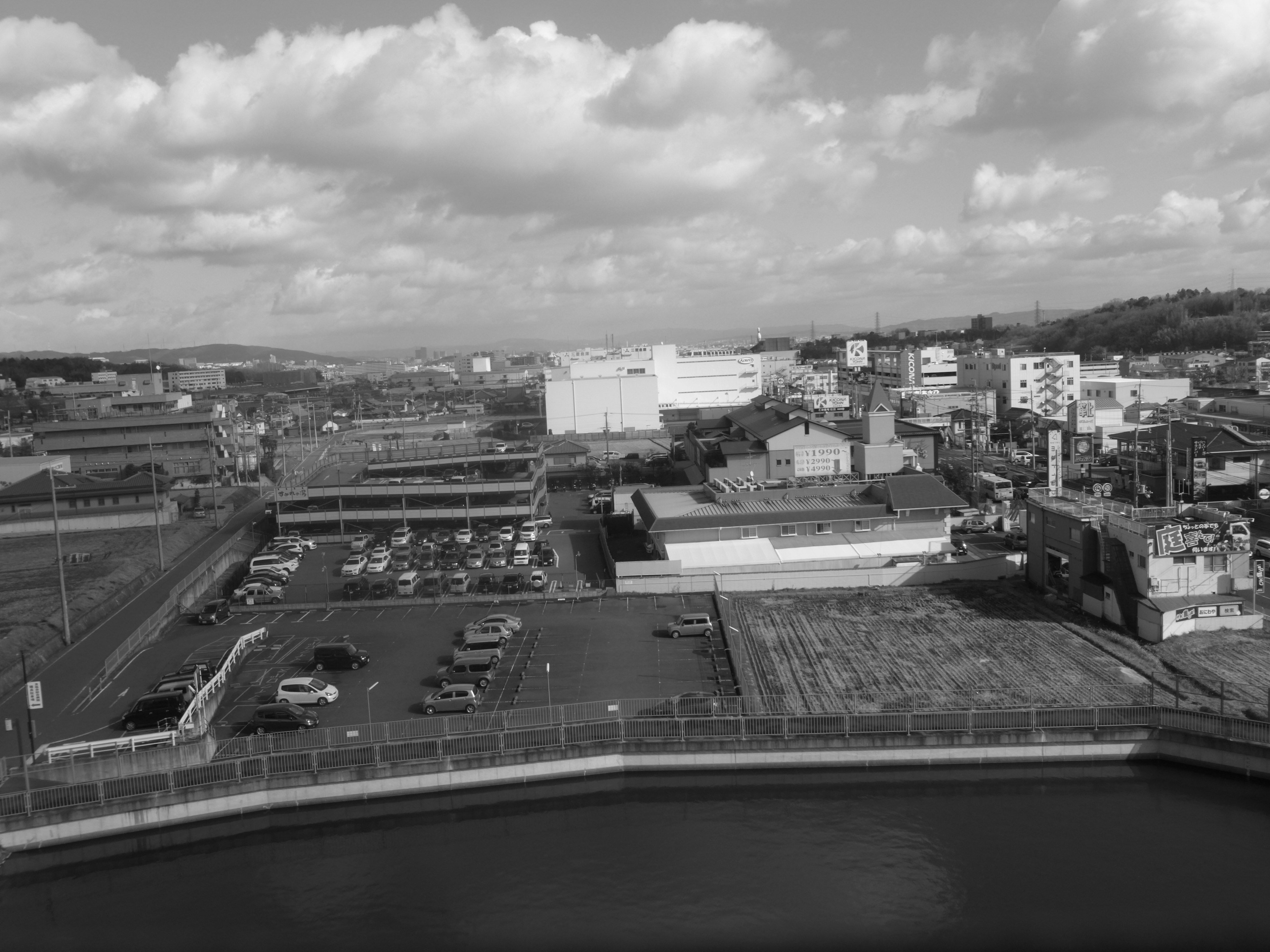 Paisaje urbano en blanco y negro con un estacionamiento y edificios circundantes