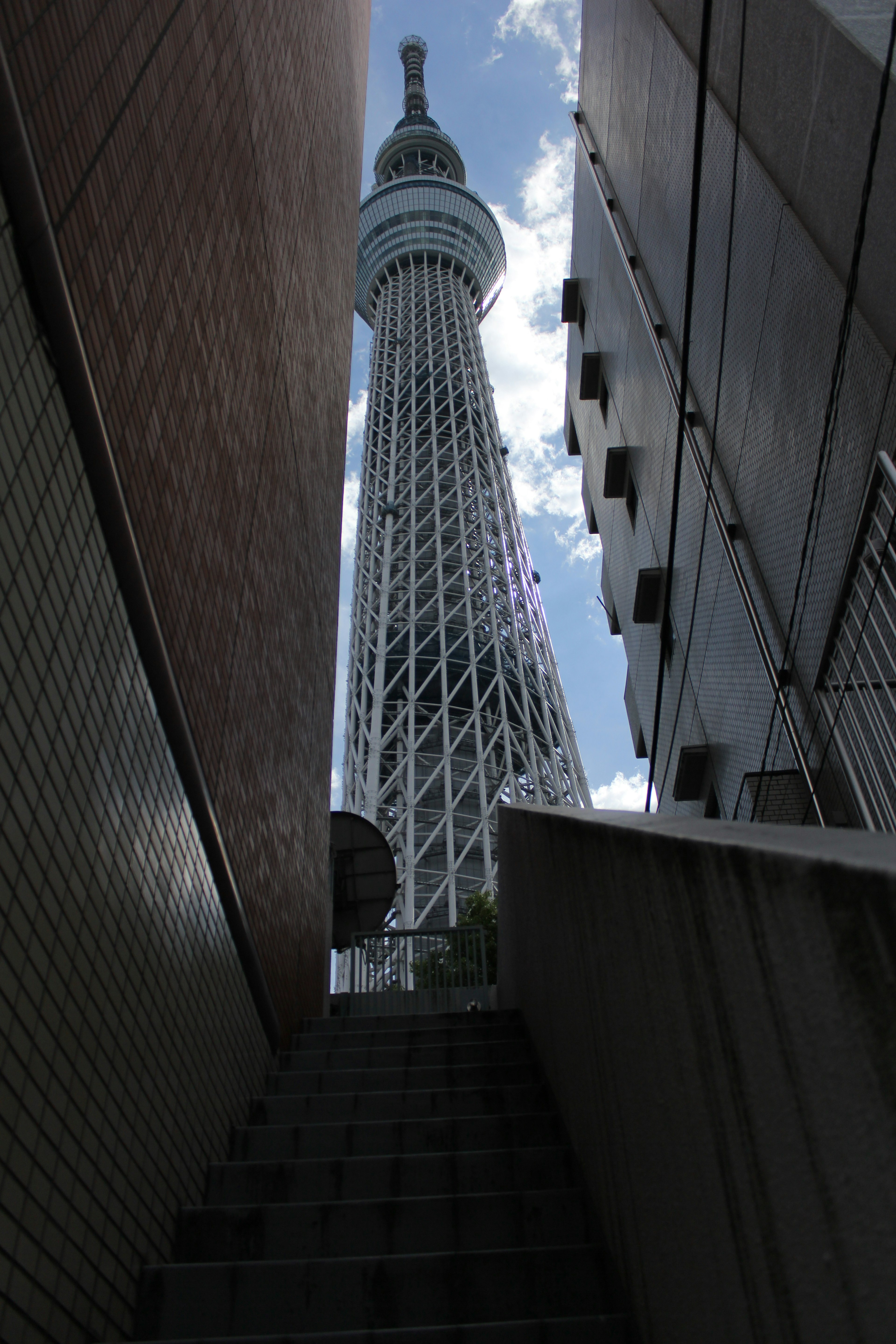 Pemandangan dari bawah Tokyo Skytree dengan bangunan di sekitar dan langit biru