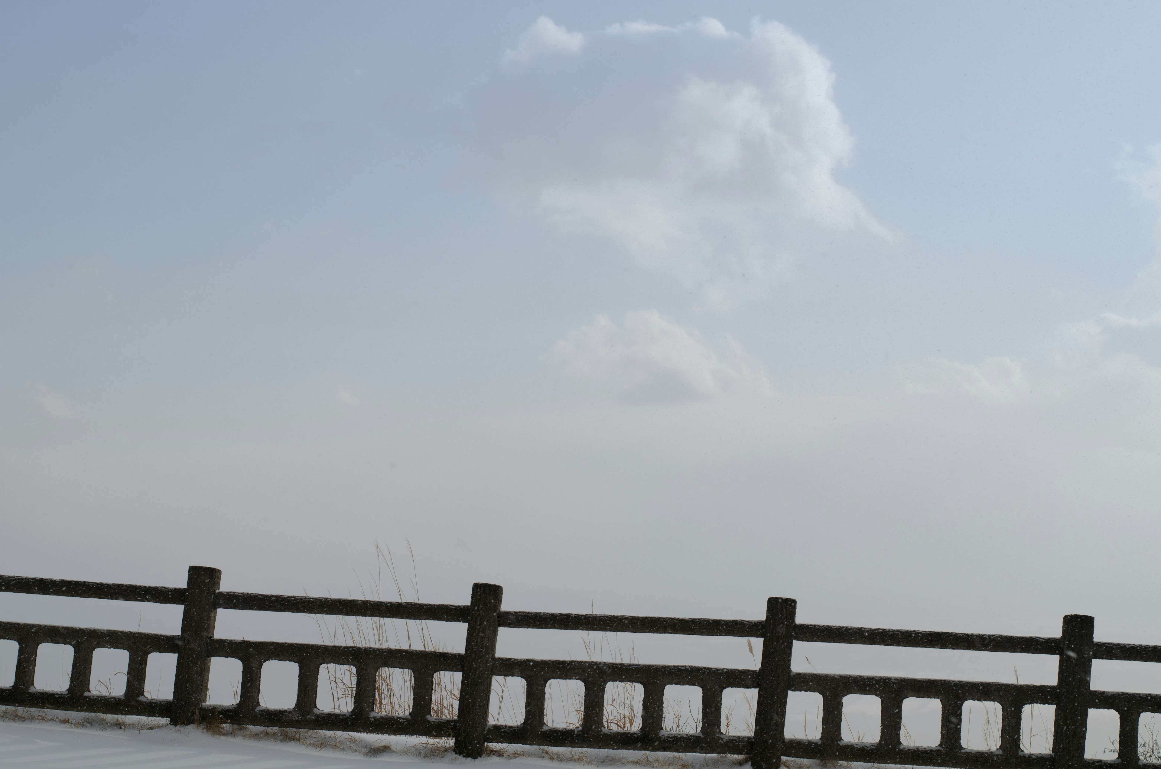 青空に浮かぶ雲とコンクリートのフェンス