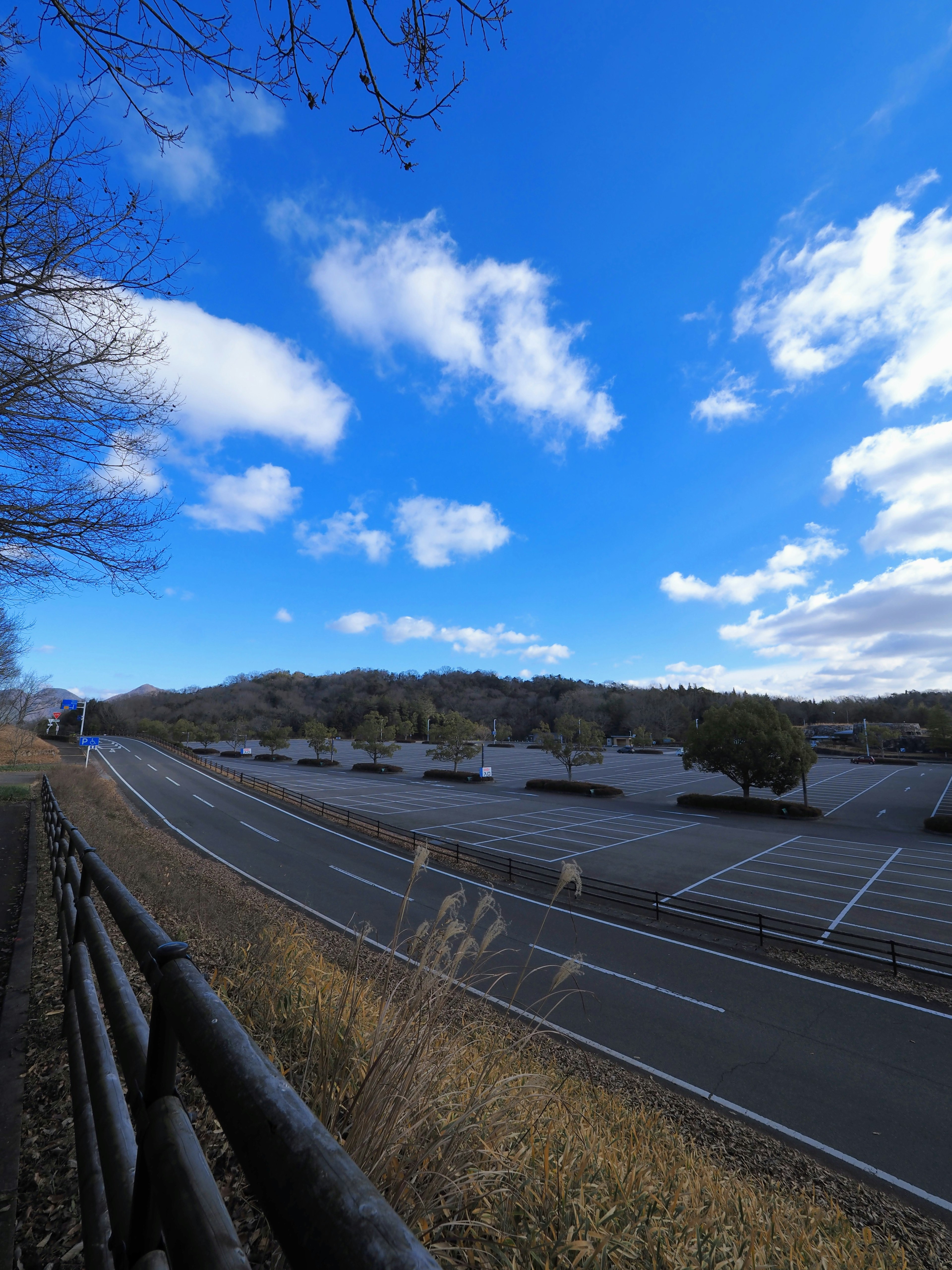 Paesaggio con cielo blu e nuvole bianche che presenta un parcheggio e una strada vicina