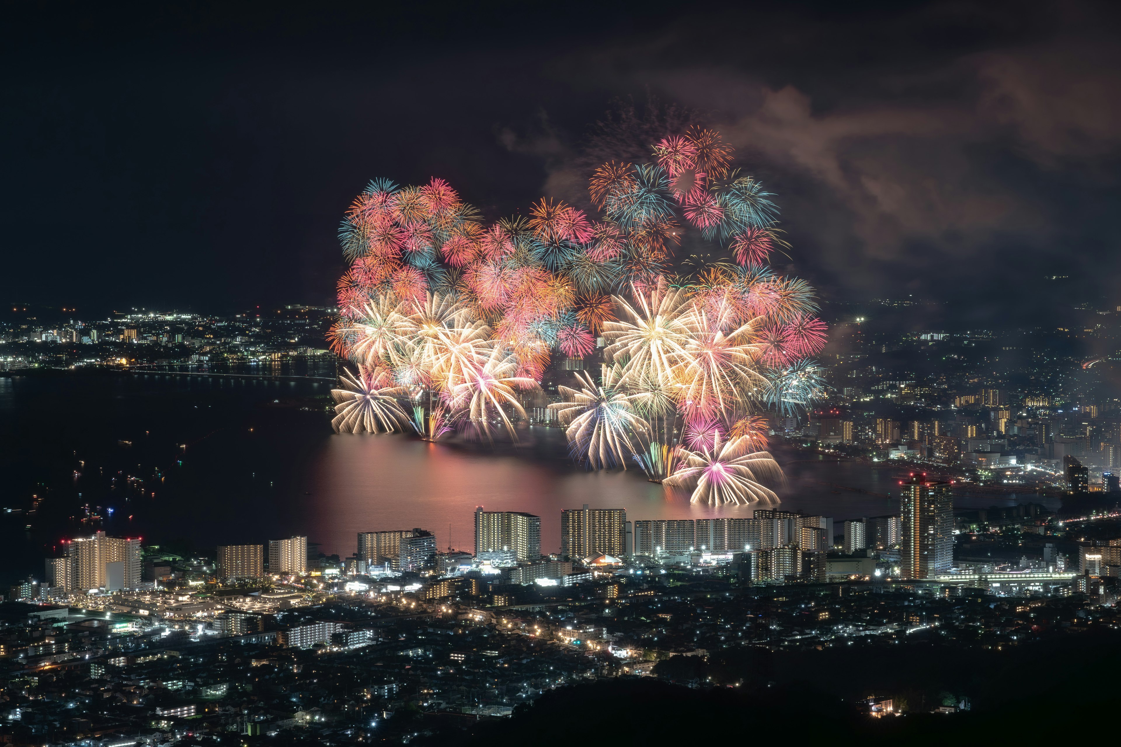 夜空に咲く色とりどりの花火と都市の夜景