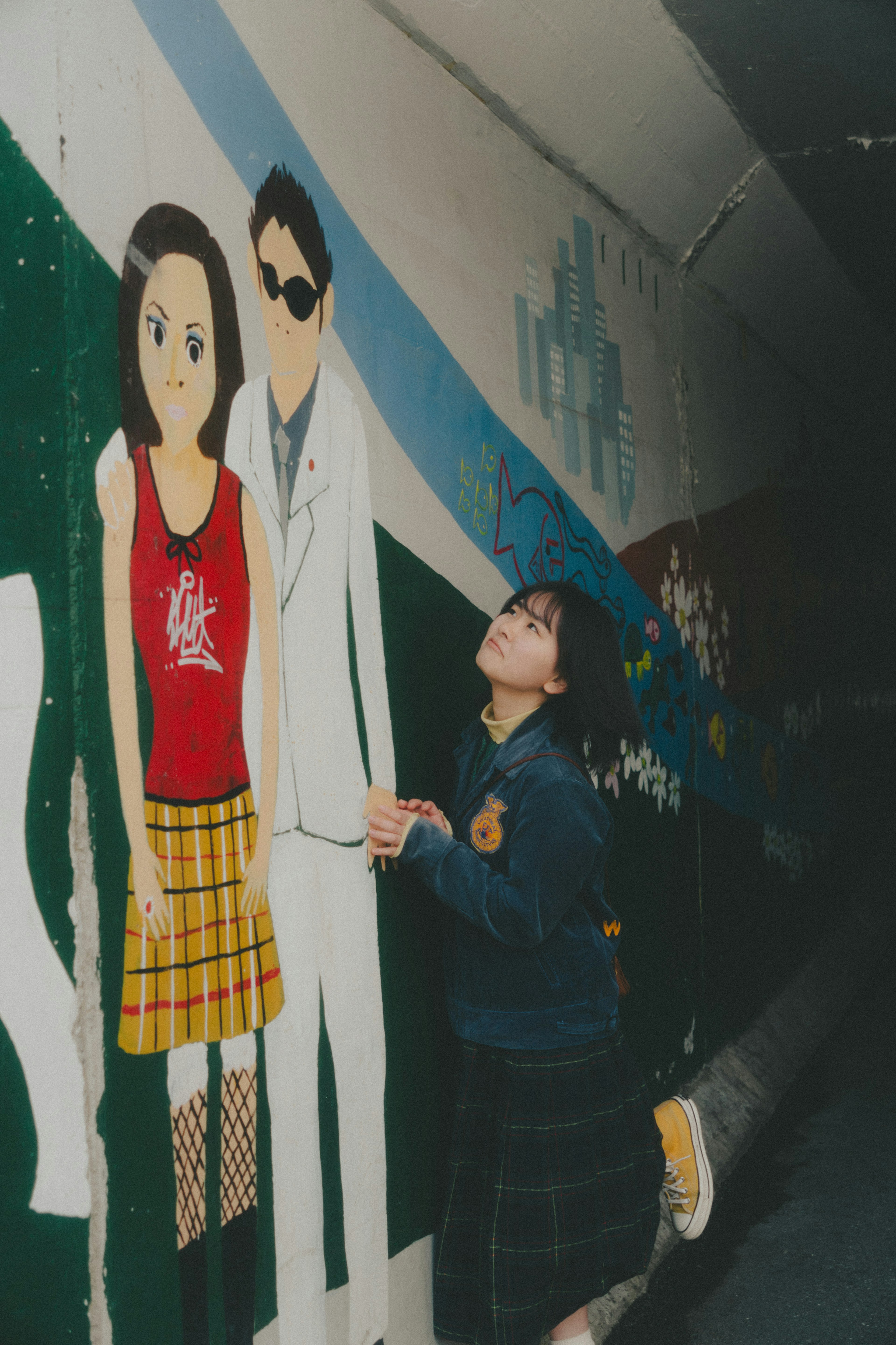 Chica posando frente a un mural con personajes de estilo anime