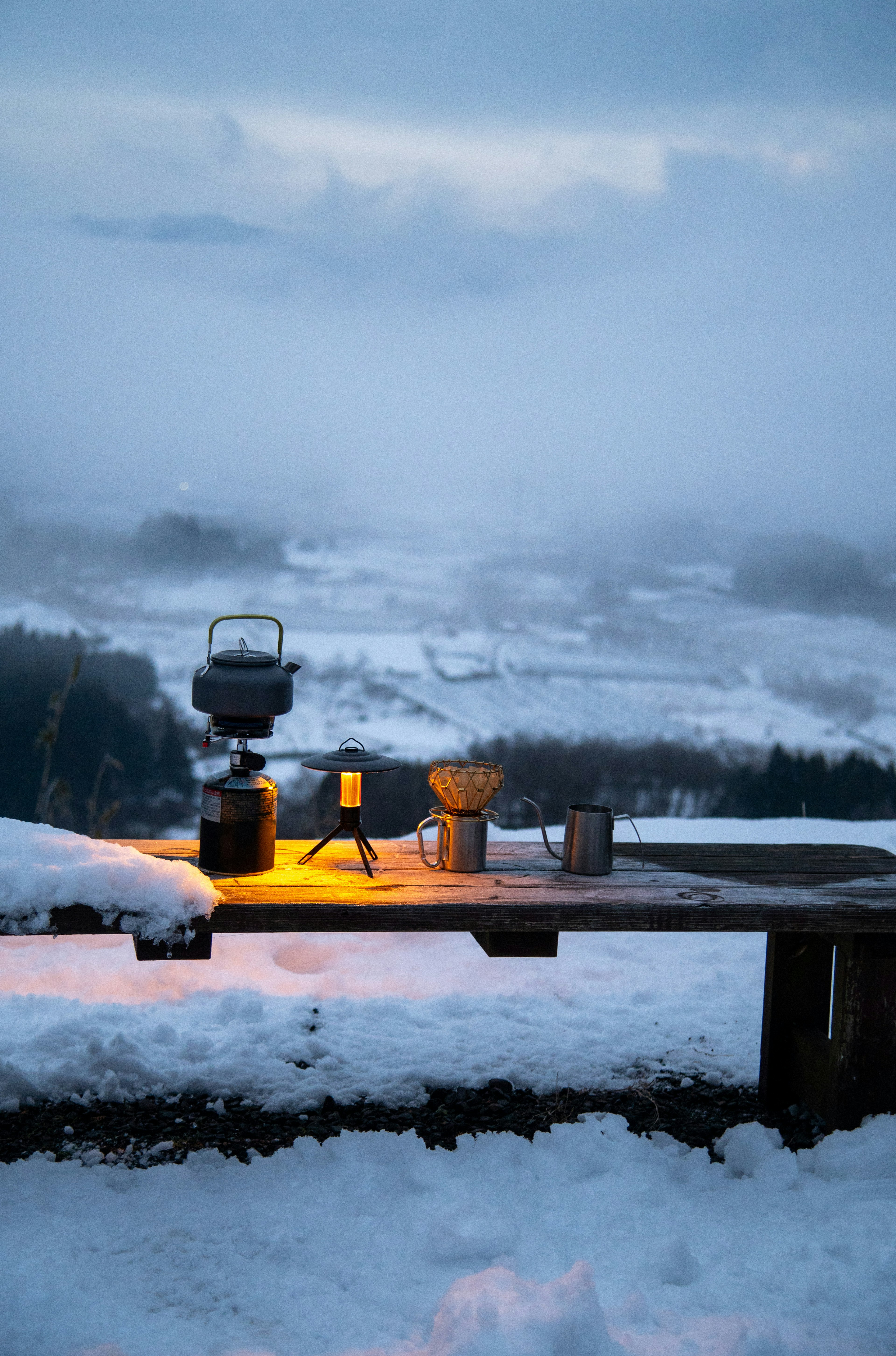 Winterszene mit einer Lampe und Kaffeegeräten auf einem schneebedeckten Tisch