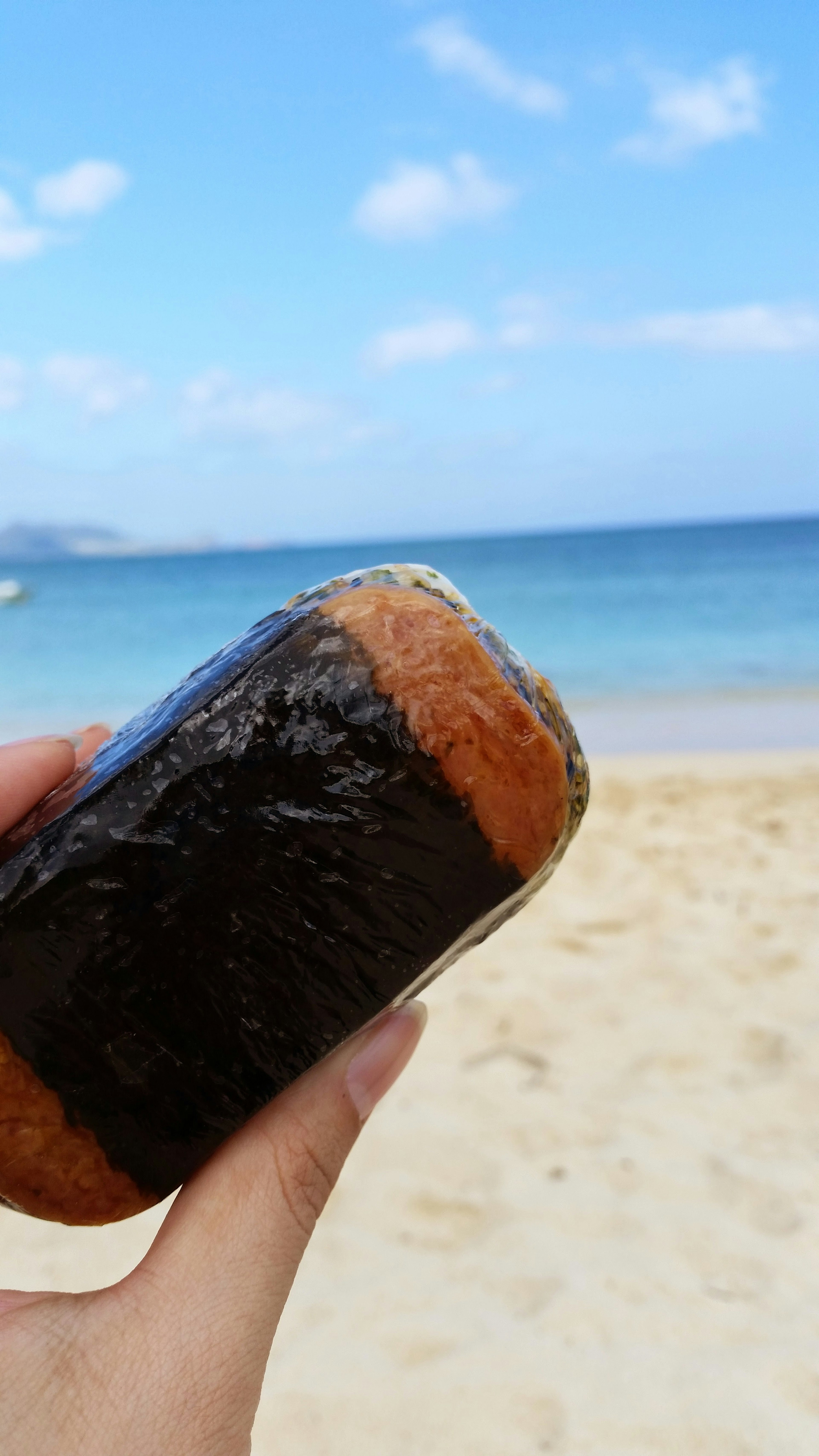 Onigiri dipegang di tangan di pantai