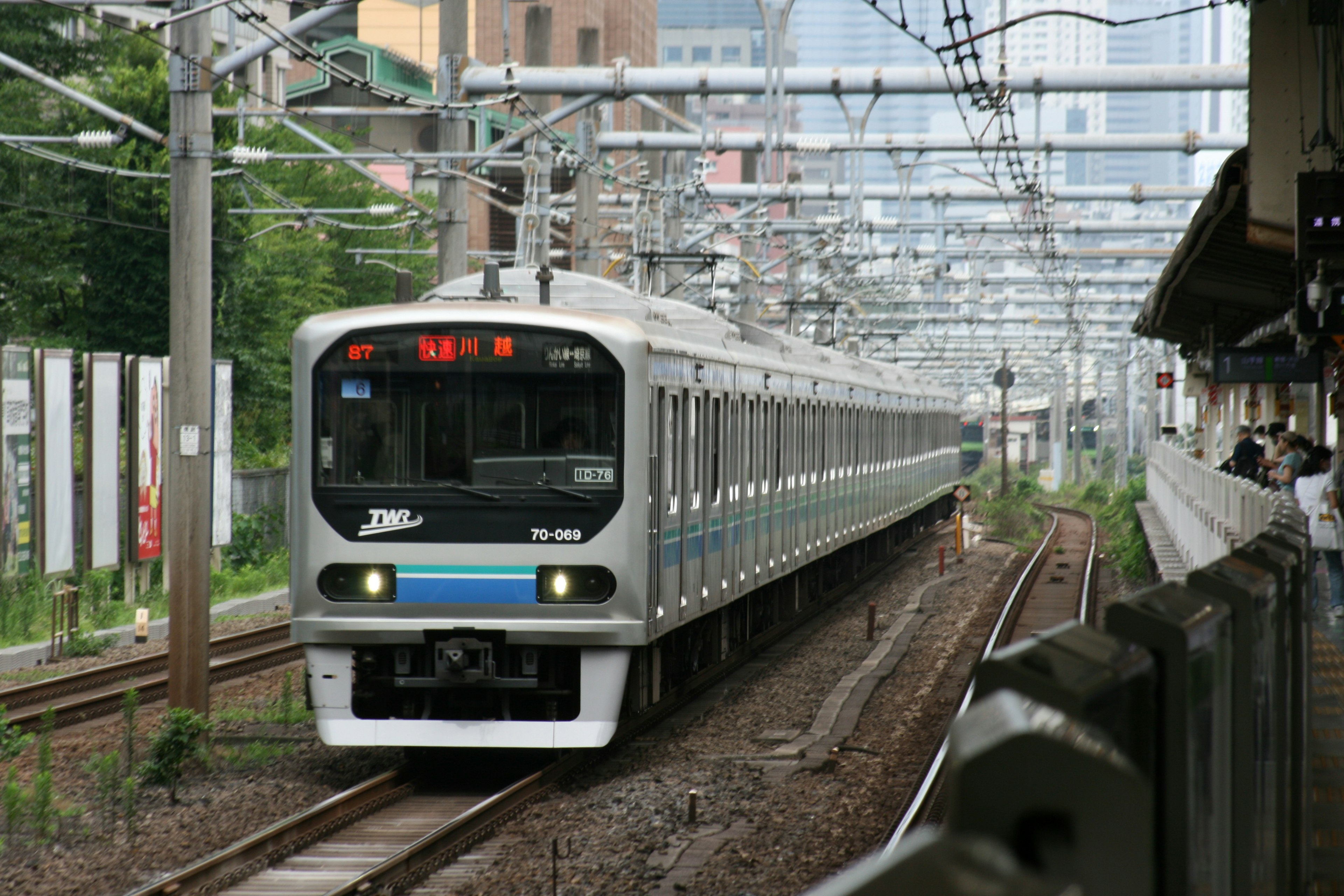 Photo d'un train sur une voie urbaine avec un train argenté et une bande bleue