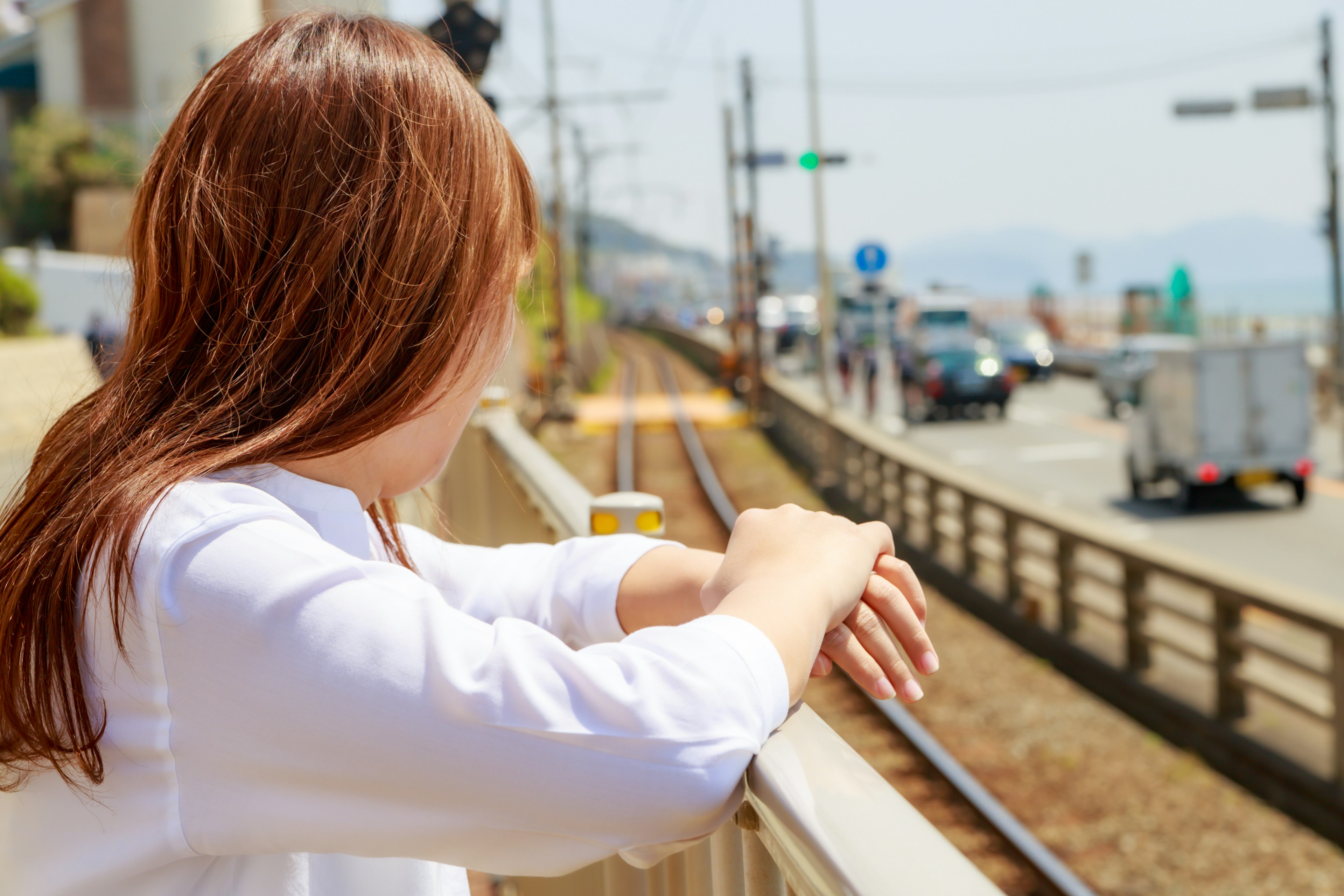 ผู้หญิงคนหนึ่งมองไปที่รางรถไฟพร้อมฉากหลังเป็นเมือง