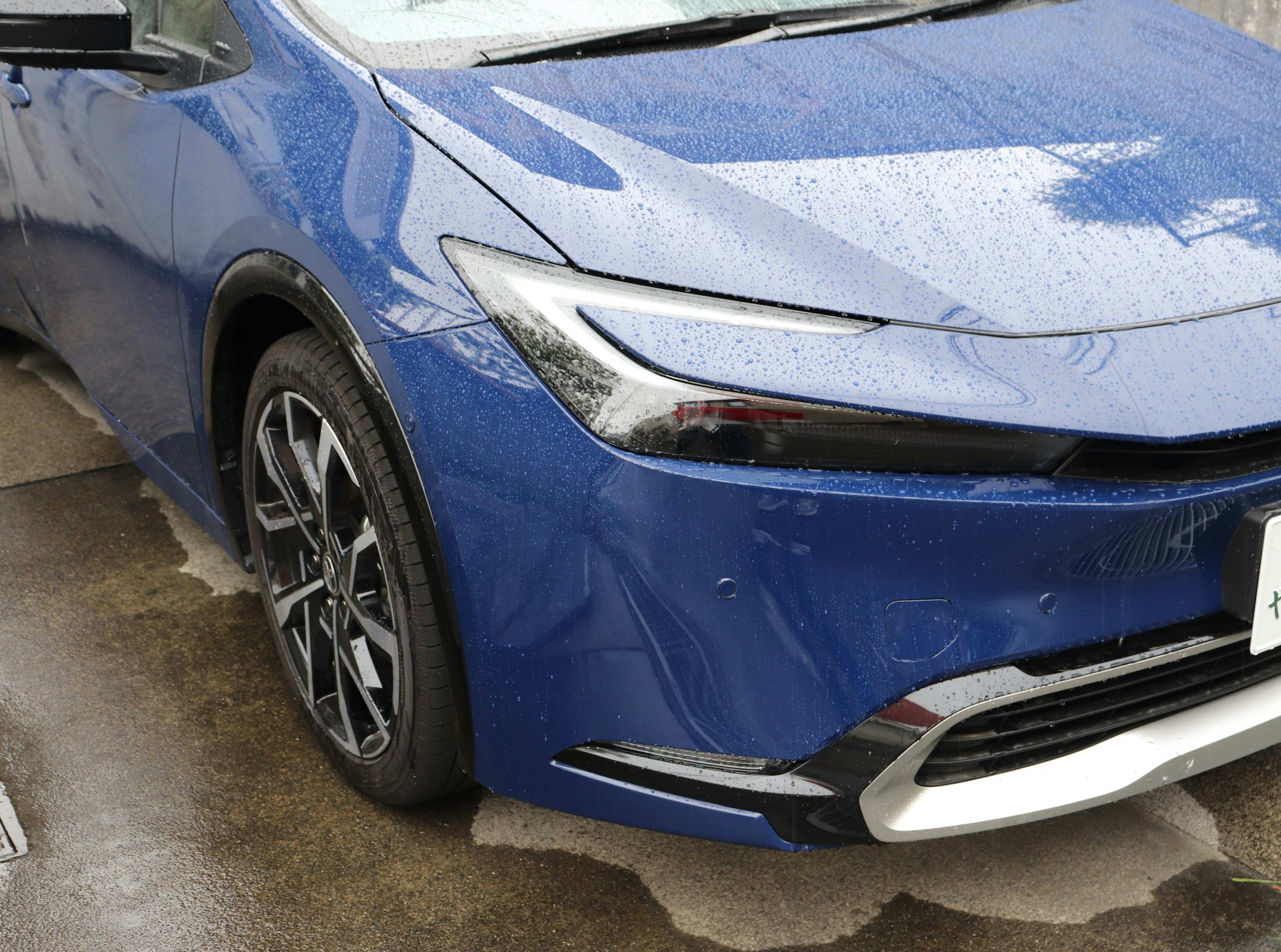 雨に濡れた青い車のフロント部分とホイール