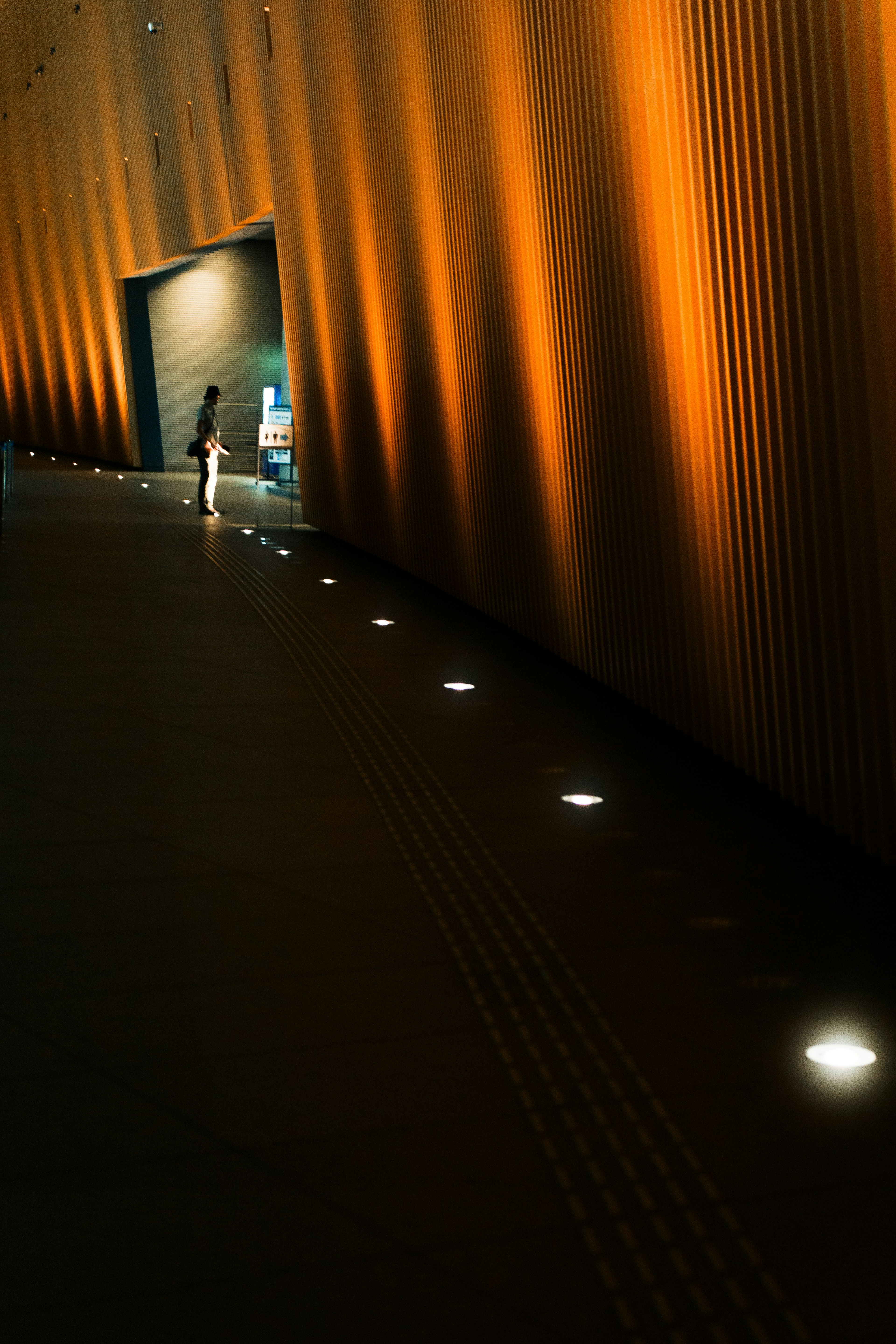 A hallway with orange wall lighting and a row of white lights along the floor