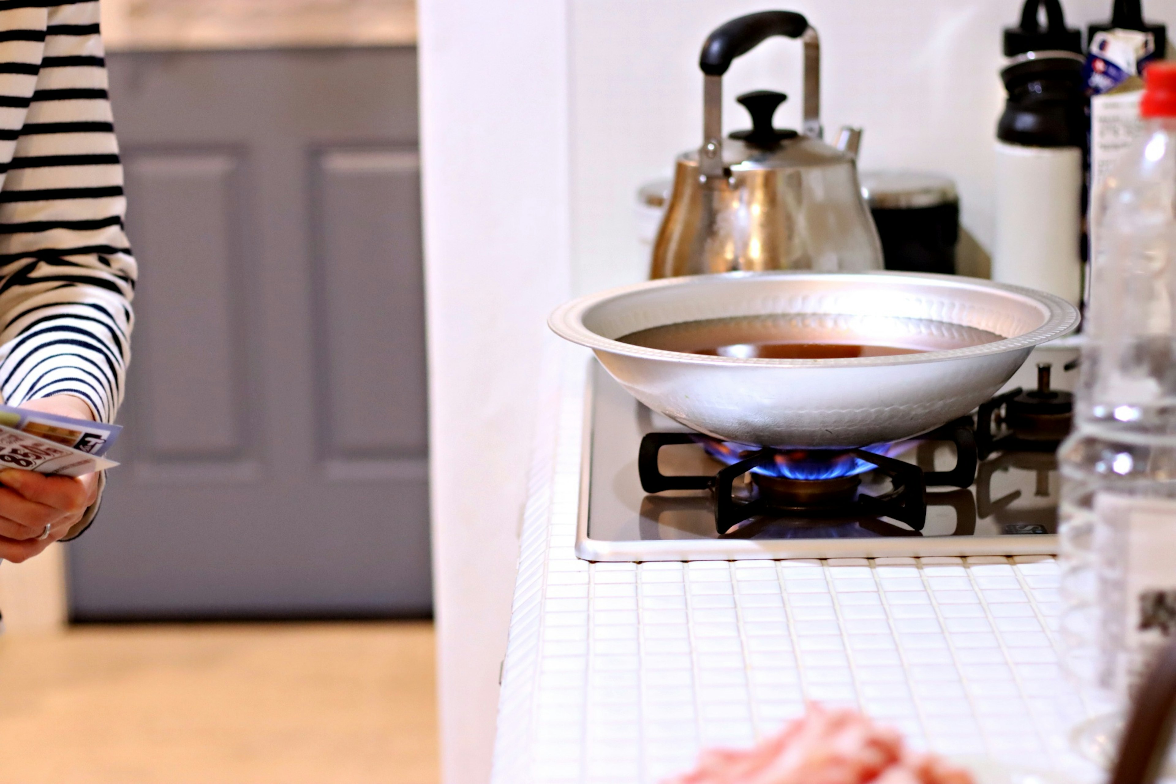 Persona cocinando en la cocina con una olla en la estufa