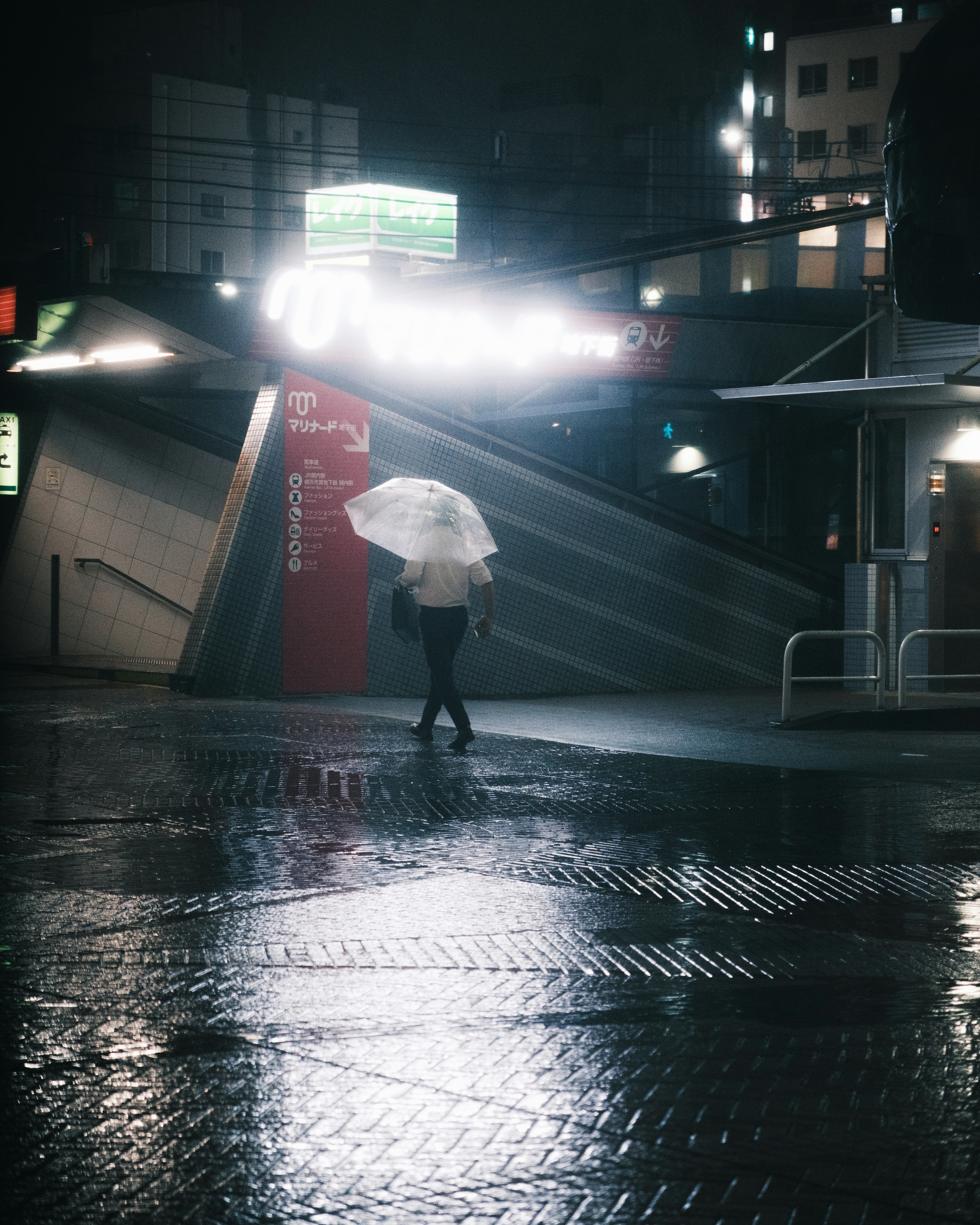 A person walking with an umbrella in a rainy urban setting at night