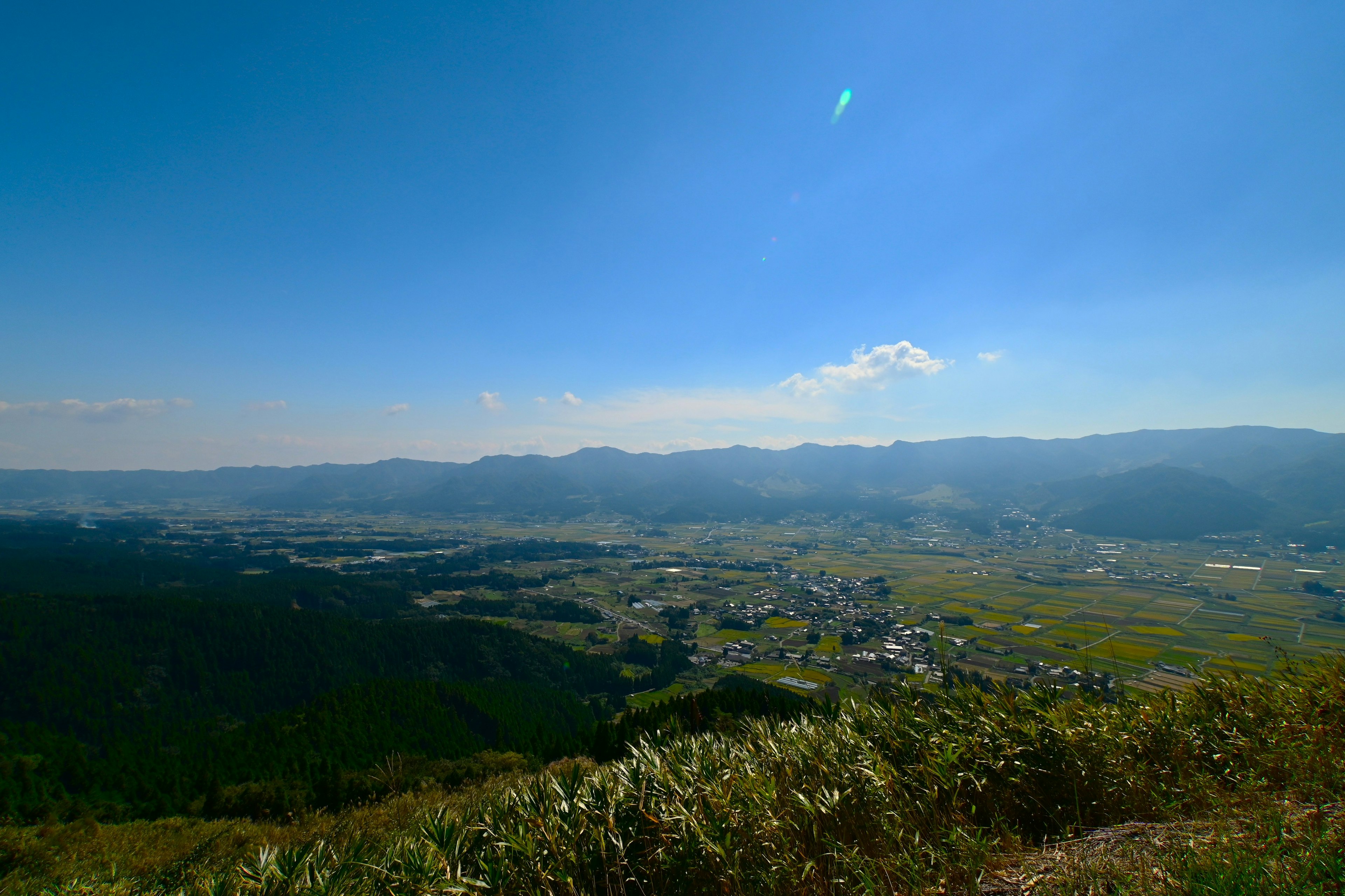 蓝天下的广阔景观，山脉与绿色田野