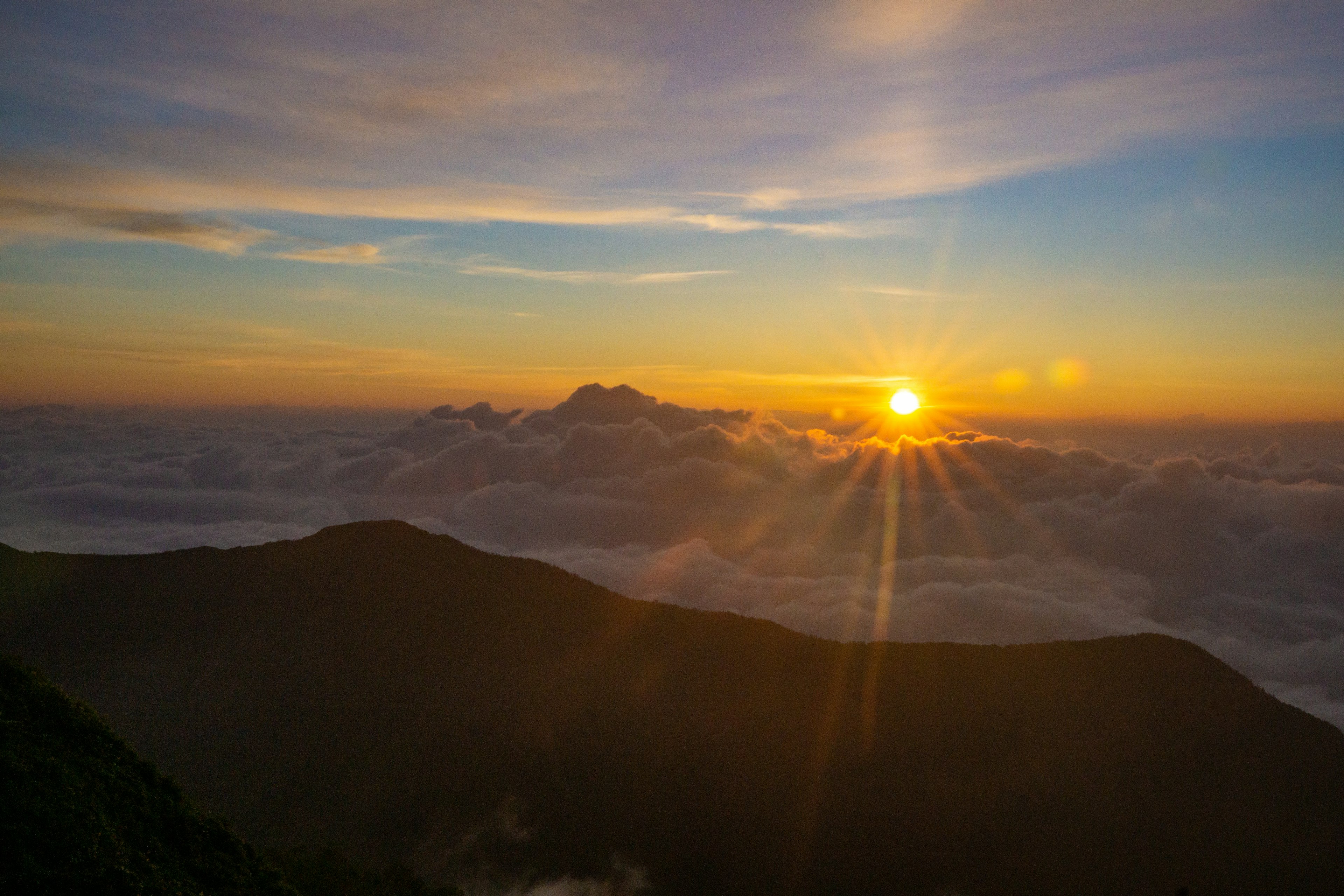 Vista dell'alba da una cima di montagna nuvole che coprono il paesaggio e sole splendente