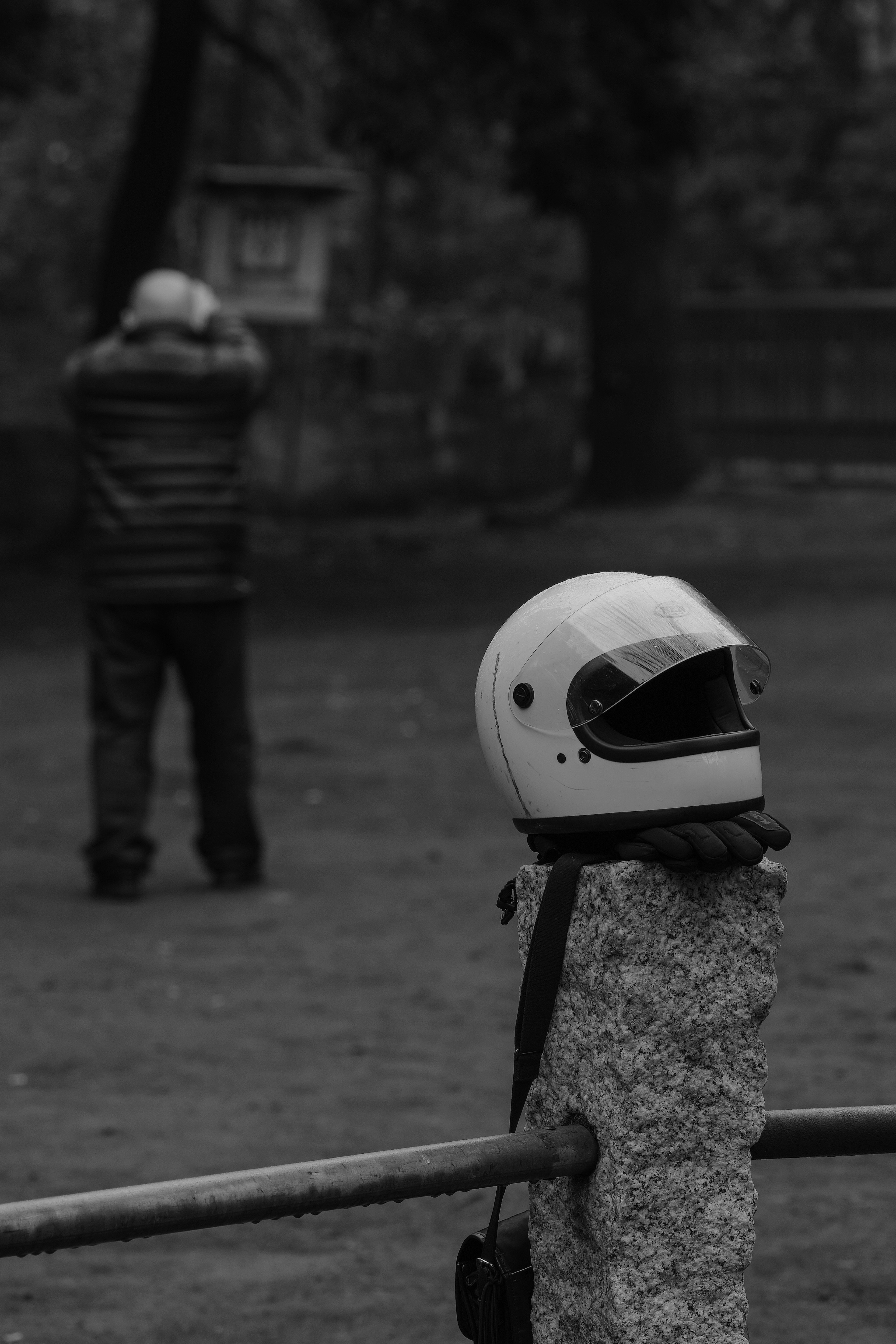 Un casco blanco colocado sobre una piedra con una persona de pie al fondo