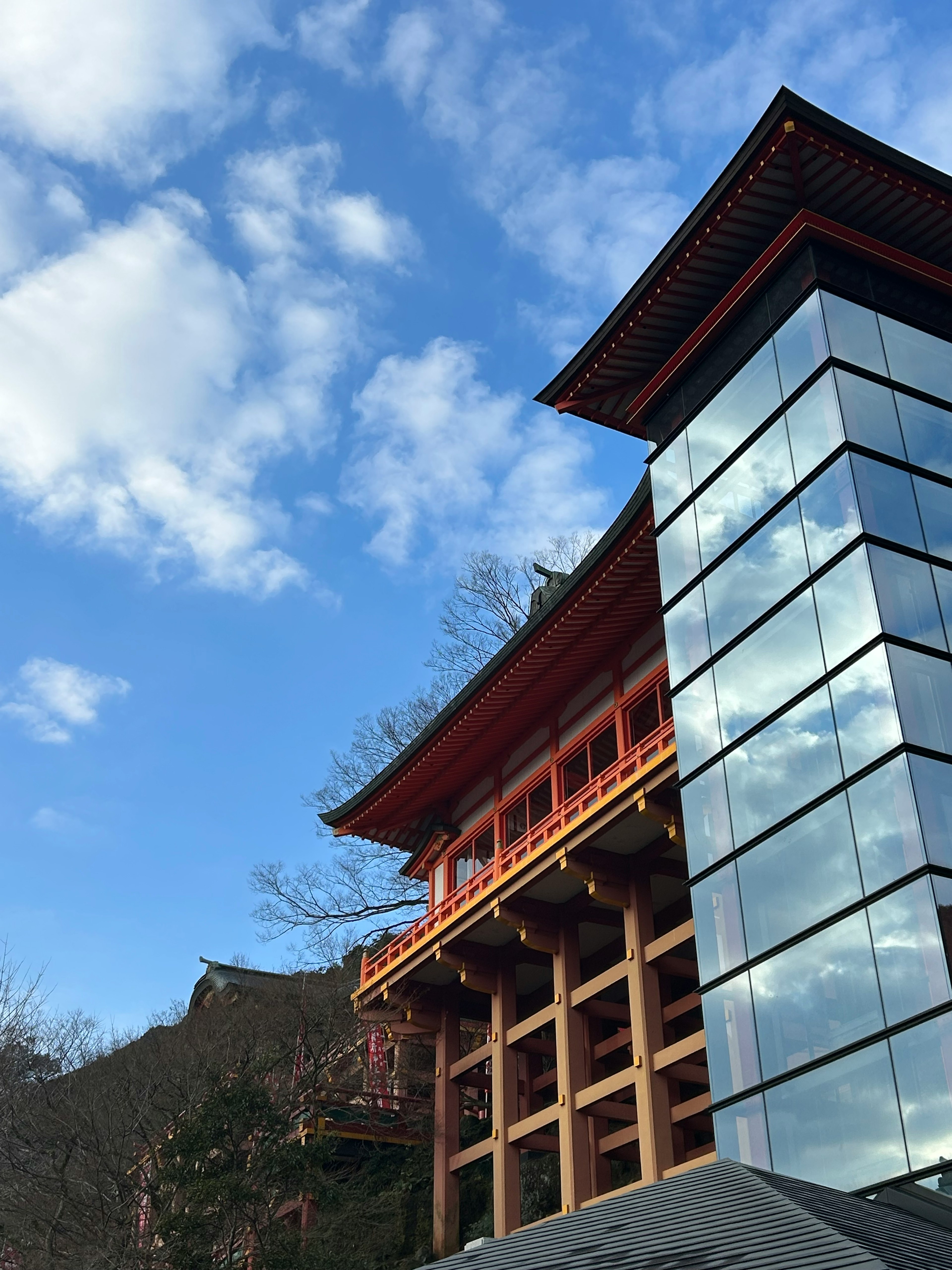 Bâtiment traditionnel rouge associé à une structure moderne en verre sous un ciel bleu