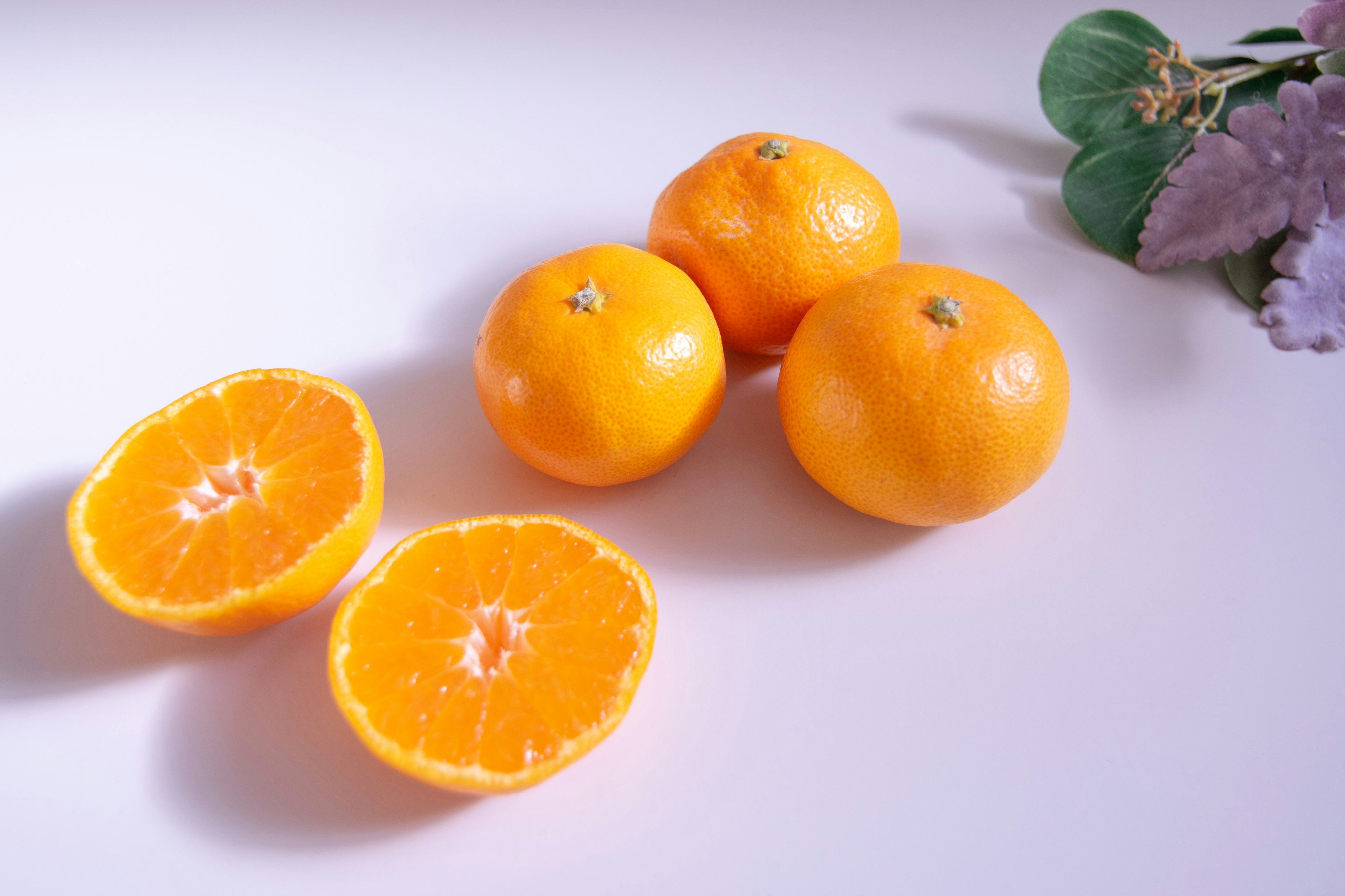 A display of whole oranges and two halved oranges on a white surface