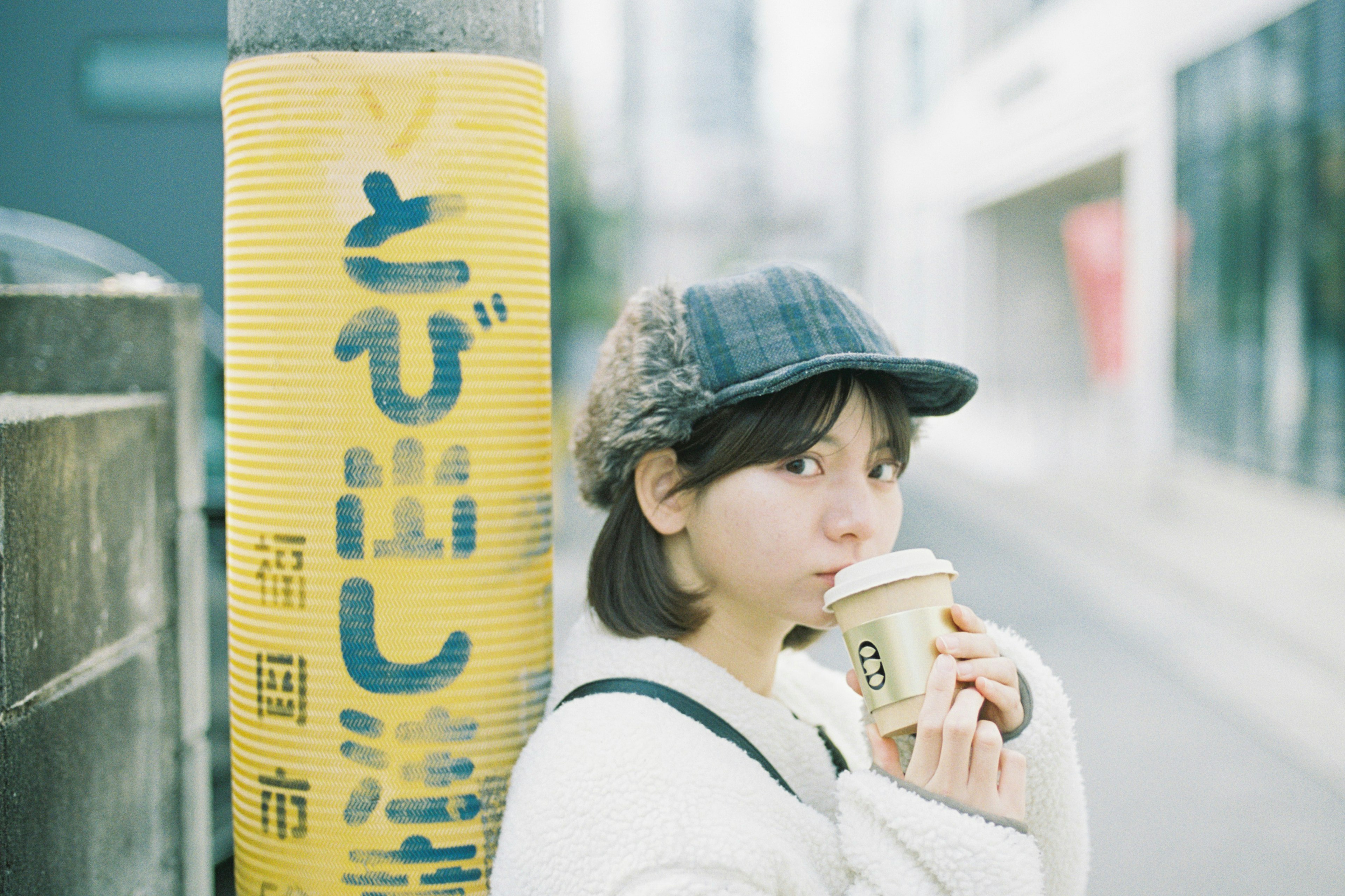 Portrait d'une femme tenant un café devant un panneau de rue