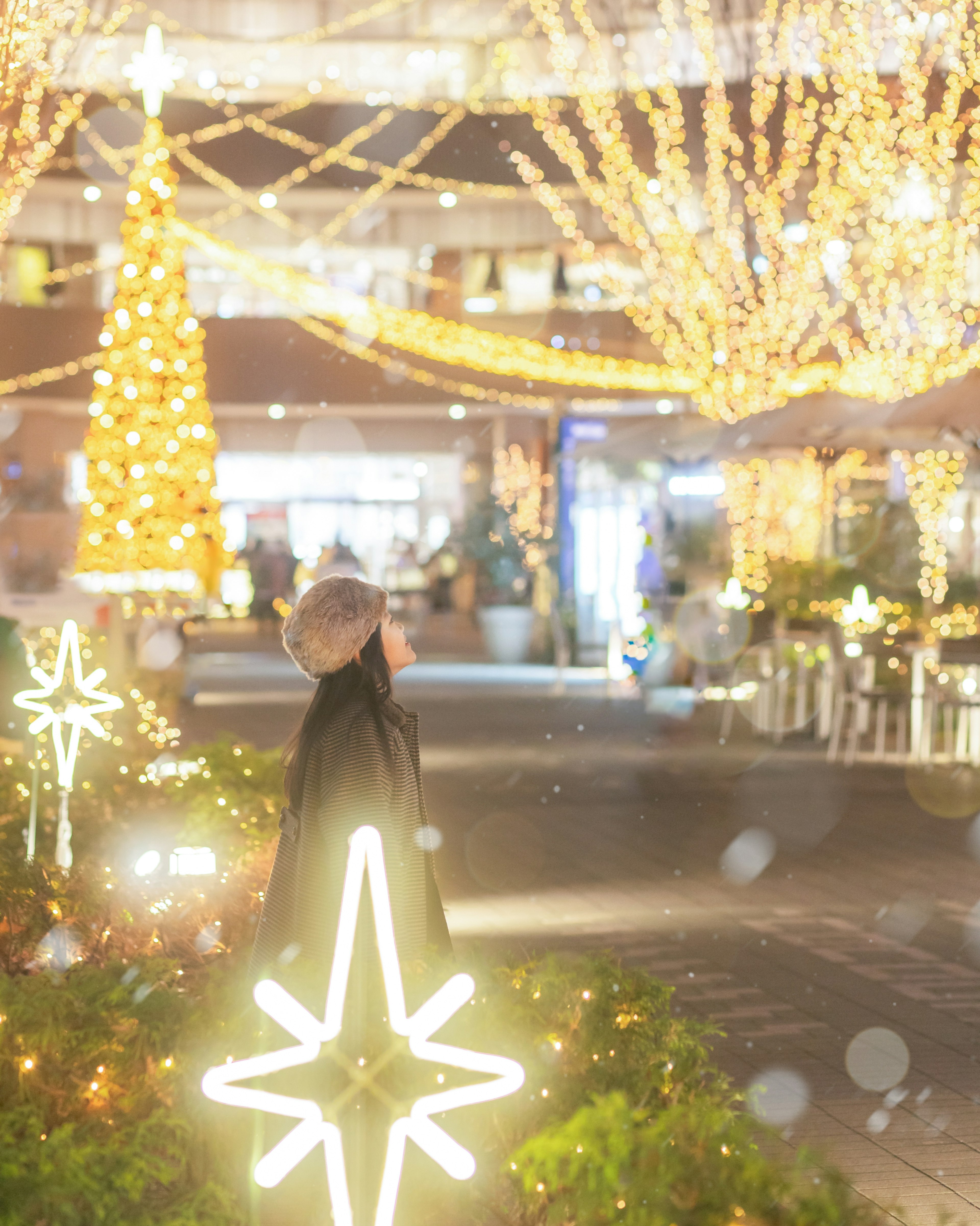 クリスマスのイルミネーションが輝く通りに立つ人物