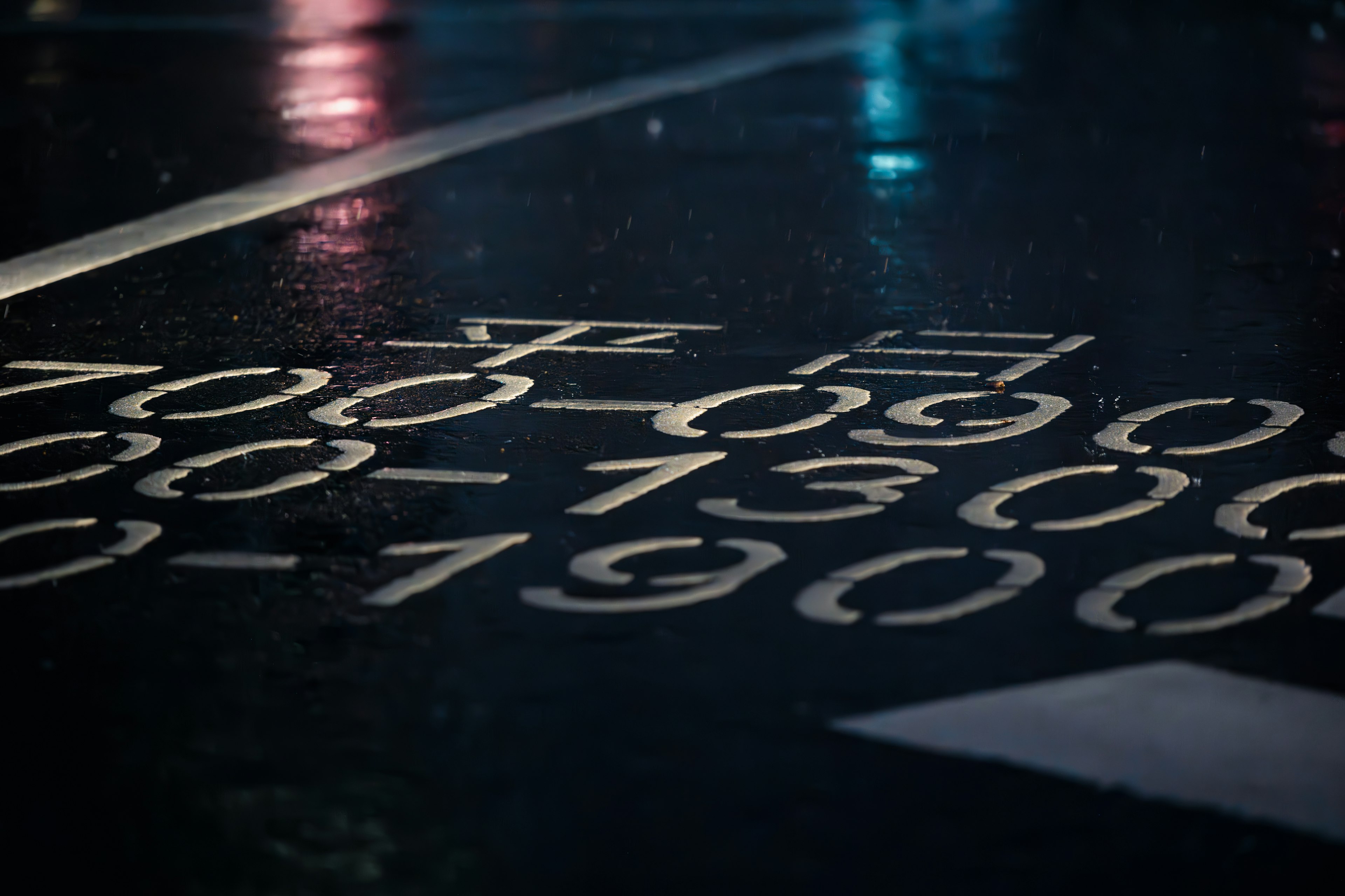 White numbers and markings indicating bicycle passage times on a wet road