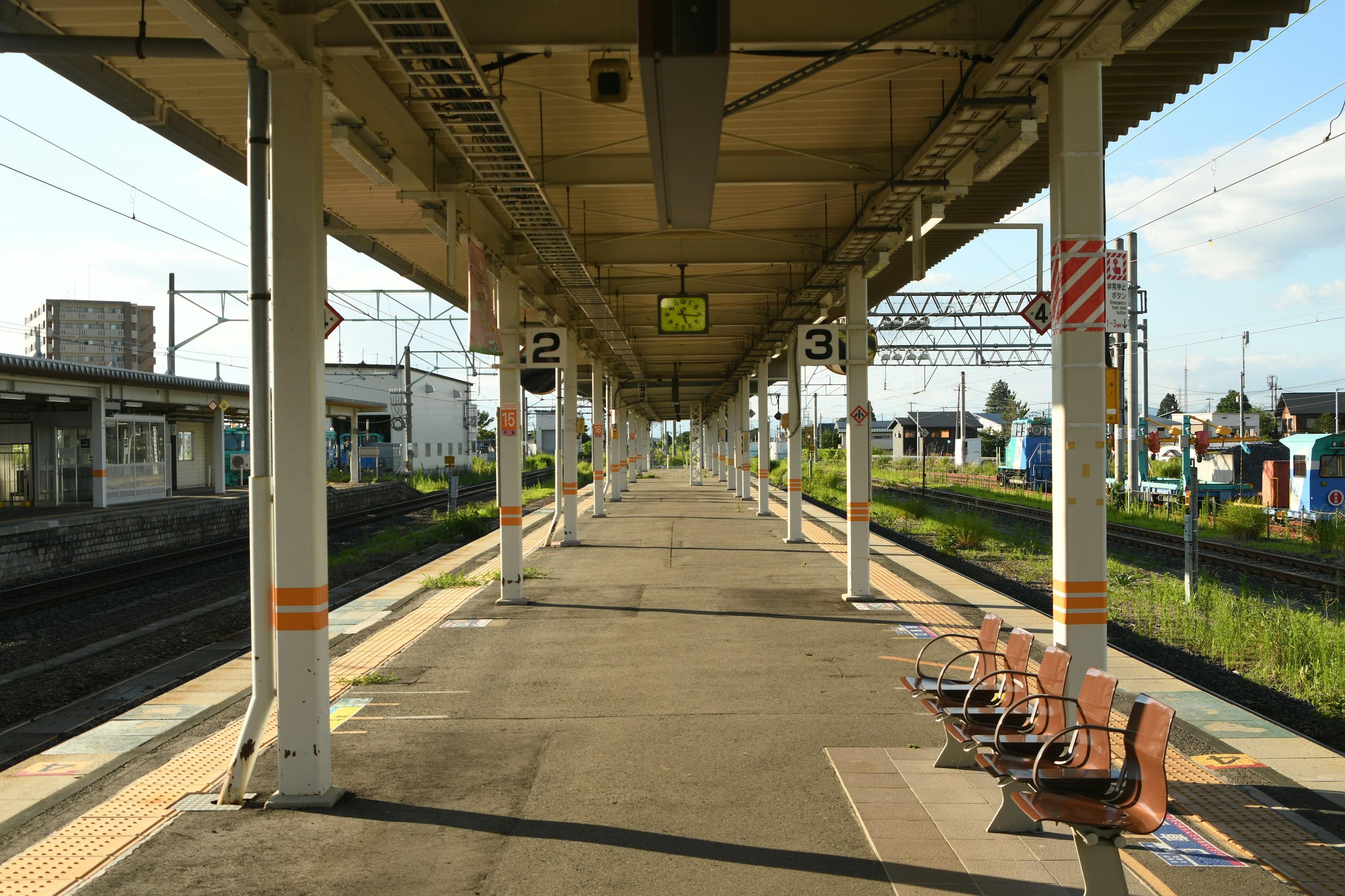 มุมมองของชานชาลาสถานีรถไฟพร้อมเสาและม้านั่งใต้ท้องฟ้าที่แจ่มใส