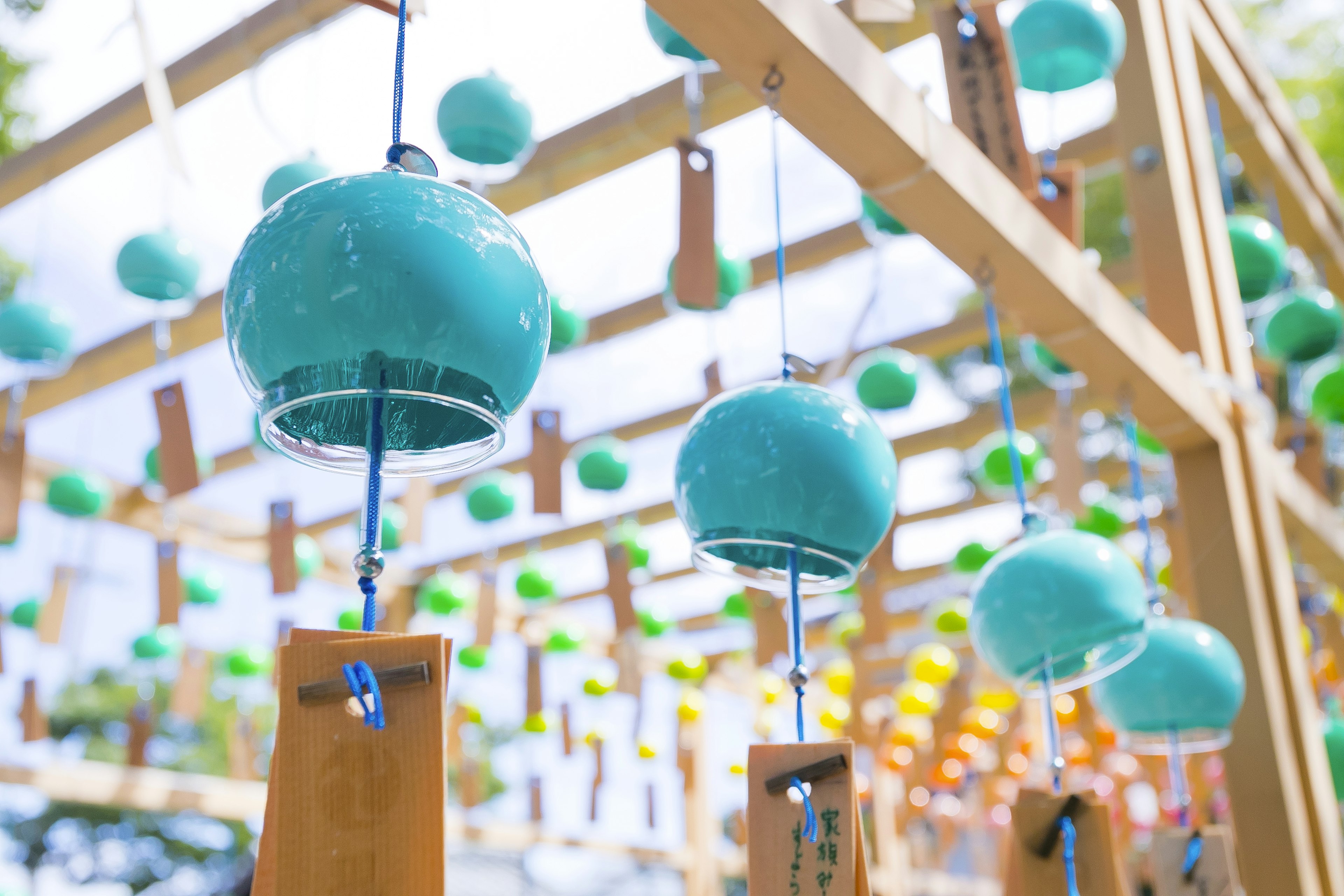 Clochettes bleues suspendues sous une structure en bois ornée de décorations vertes et jaunes