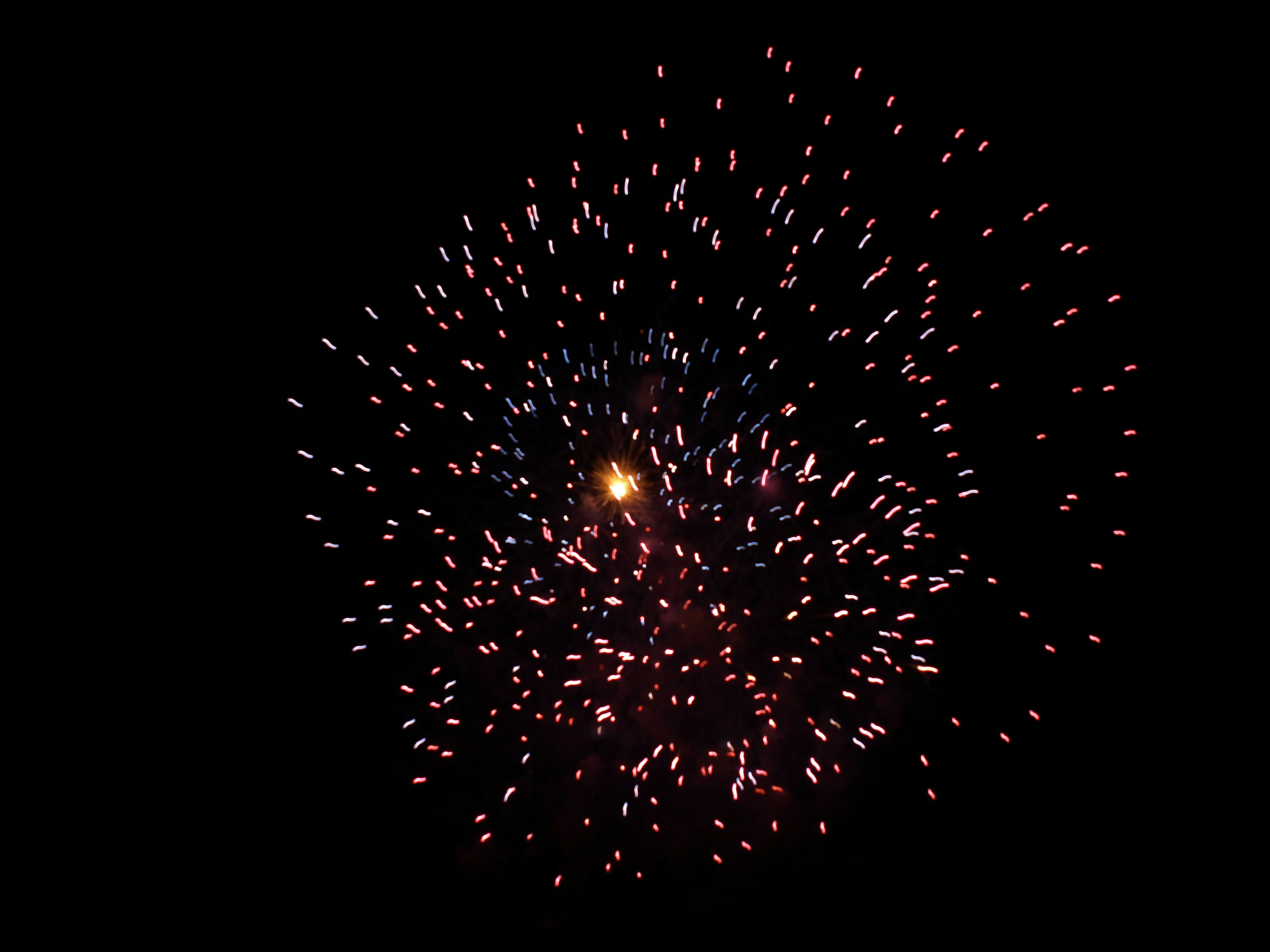 Explosión de fuegos artificiales sobre fondo oscuro chispas rojas y azules vibrantes que se dispersan