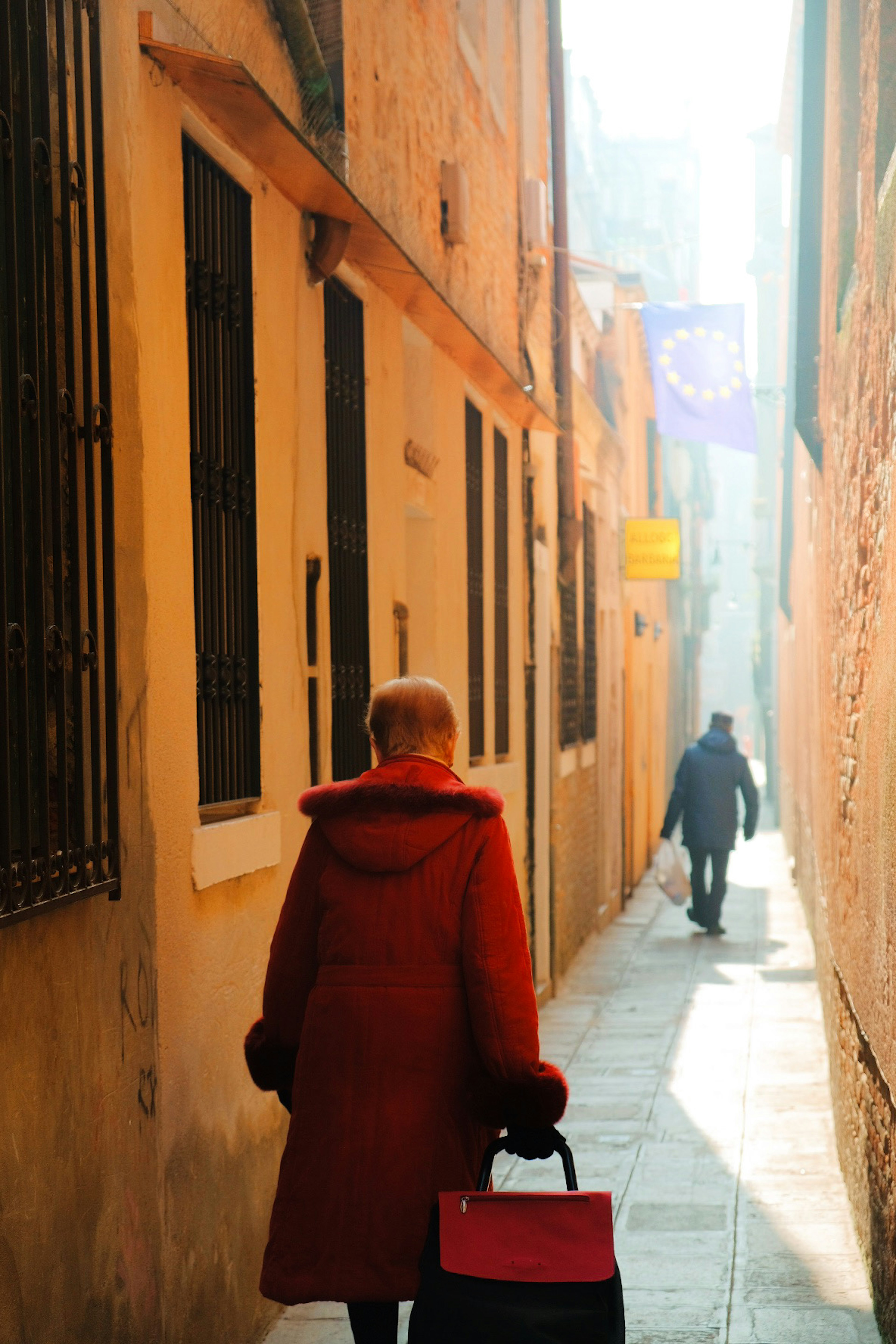 Una mujer con abrigo rojo caminando por un callejón estrecho