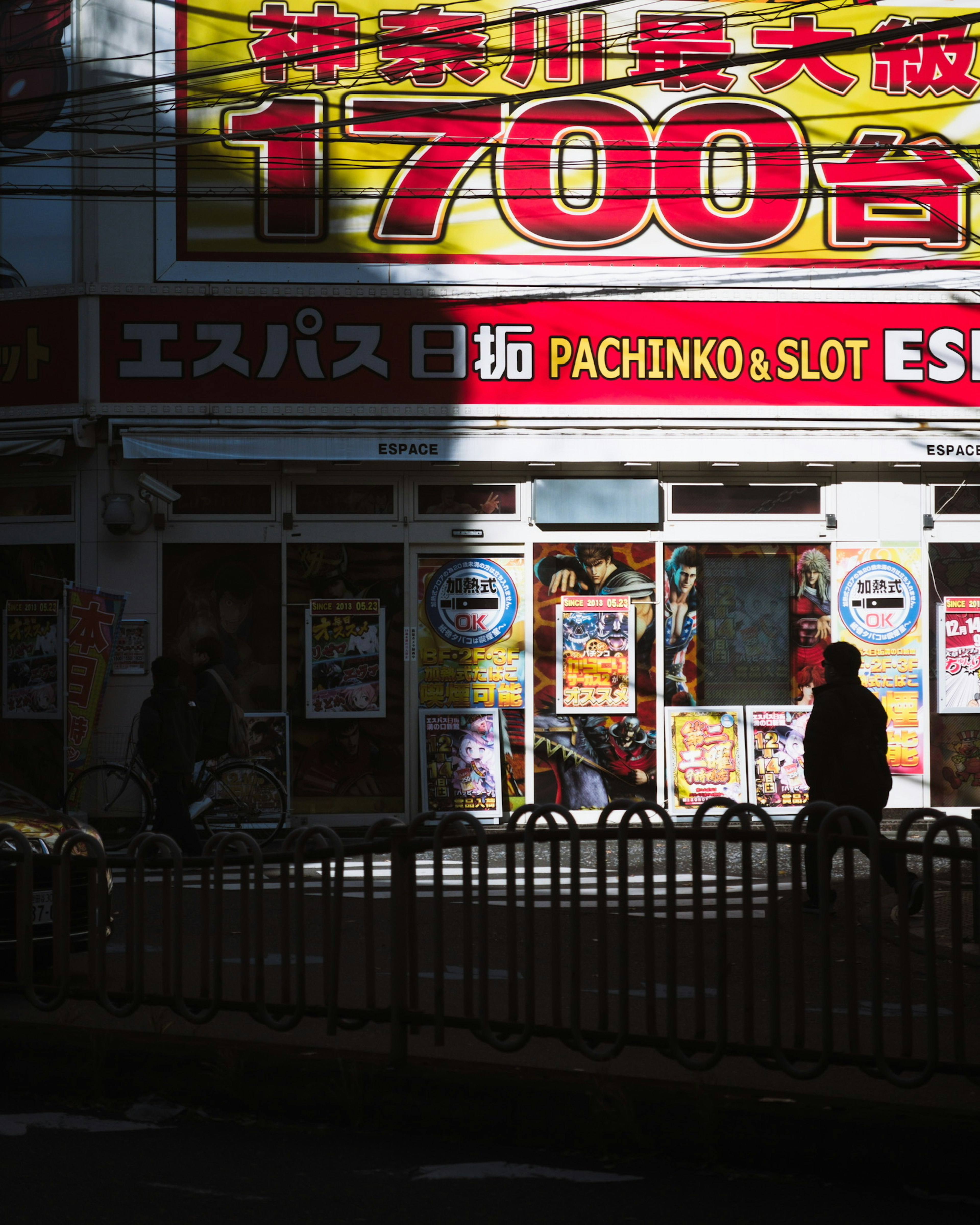 明るい看板のあるパチンコ店の外観と影の中の人