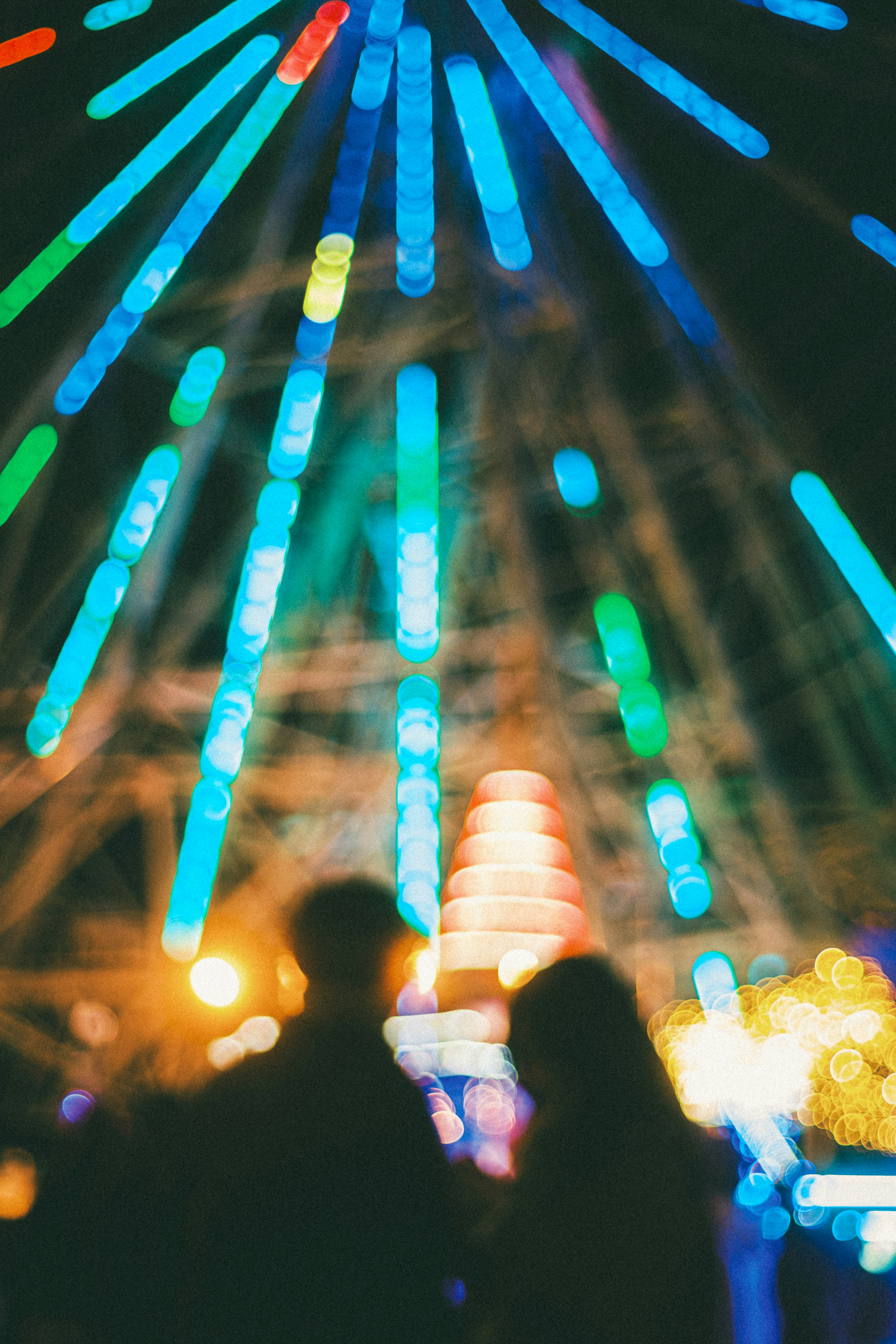 Silhouette eines Paares vor einem bunten Riesenrad bei Nacht