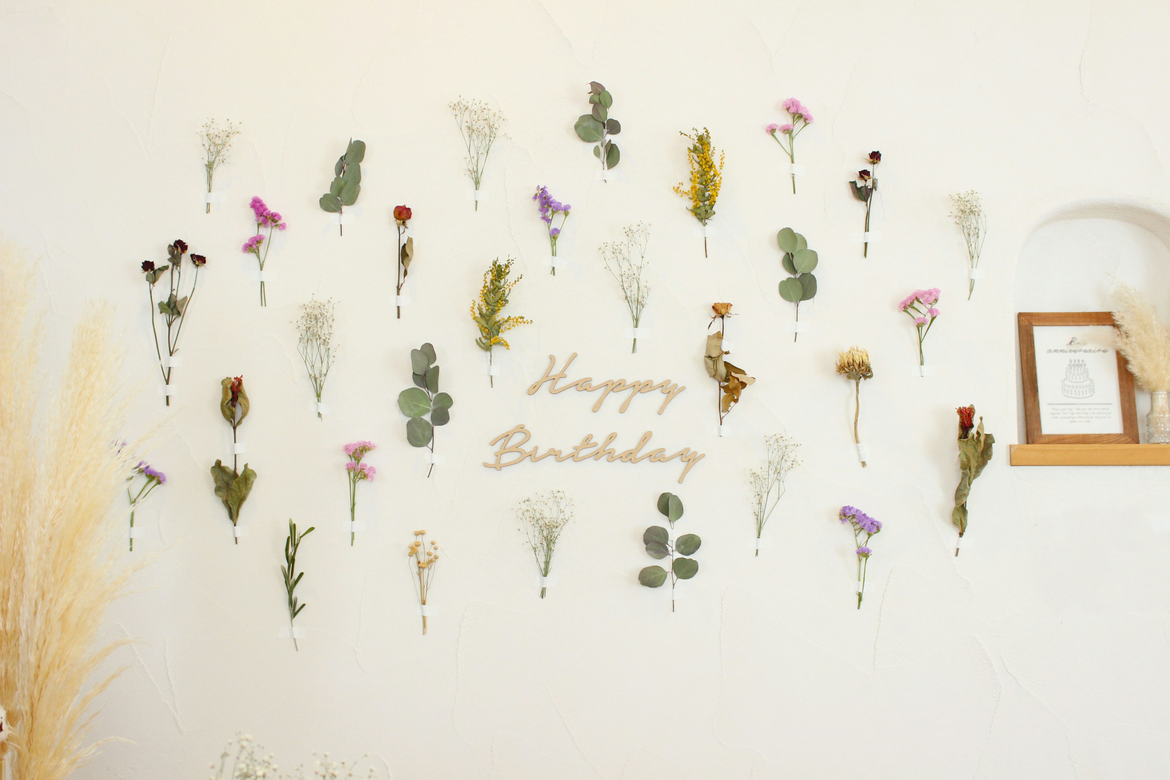 A wall decorated with dried flowers and the text 'Happy Birthday'