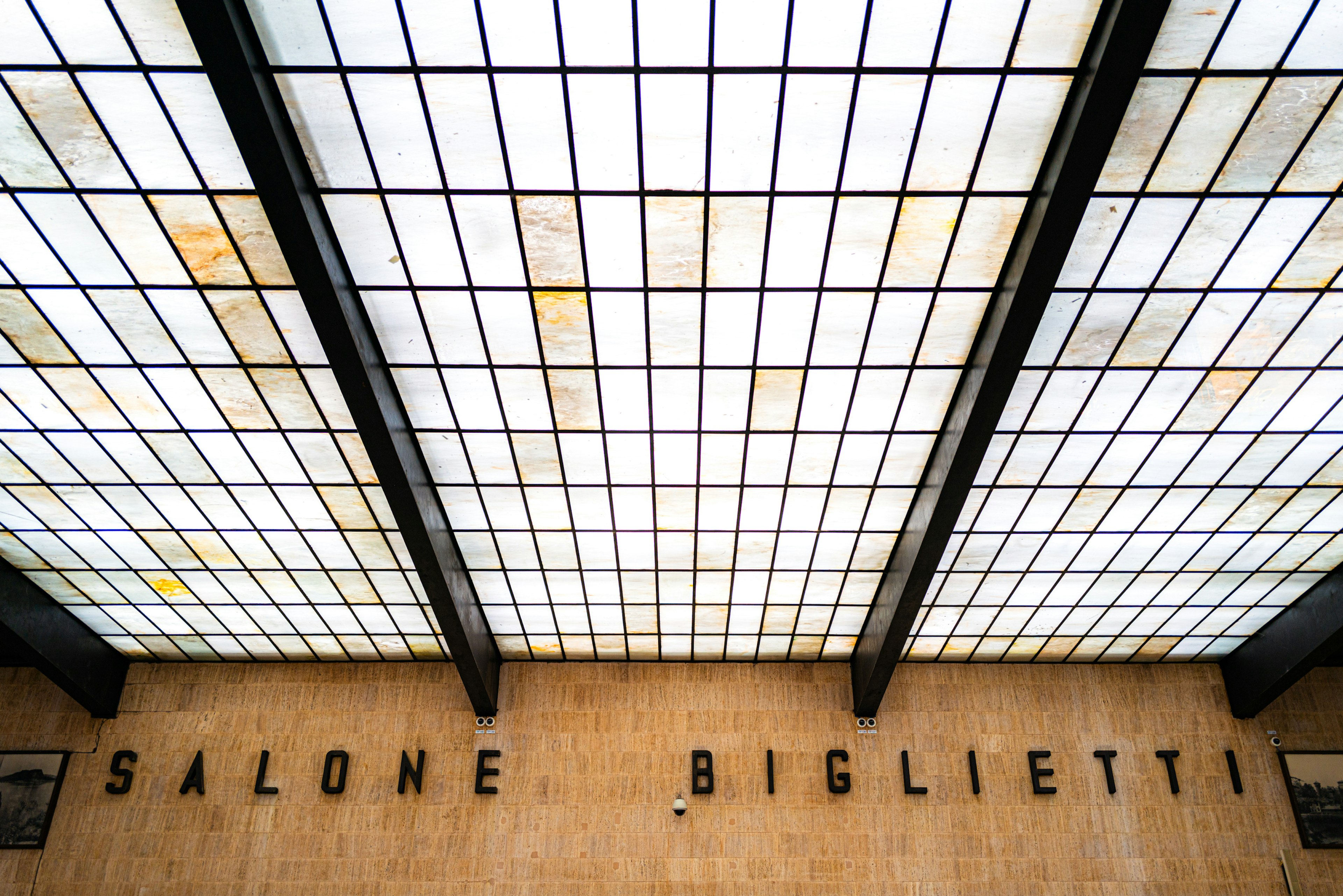 Vue intérieure d'un bâtiment avec des panneaux de verre au plafond et le panneau Salone Biglietti