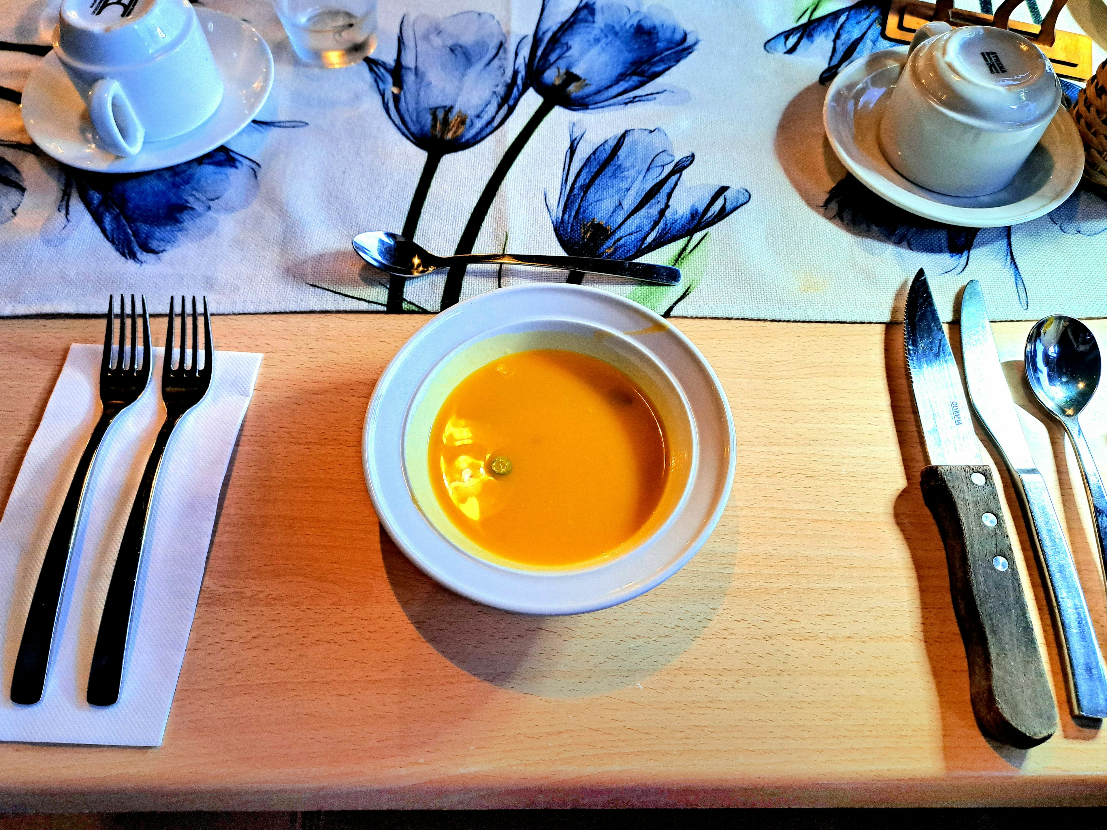 Mesa dispuesta con un tazón de sopa cremosa y cubiertos