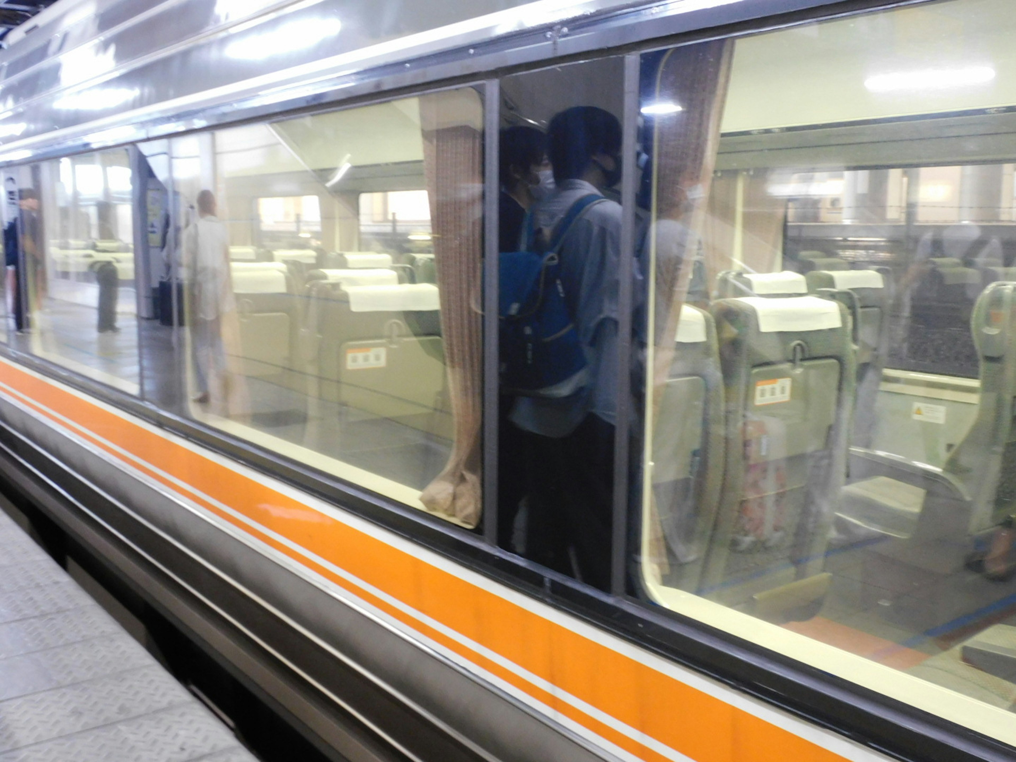 駅での電車の窓越しに見える座席と人