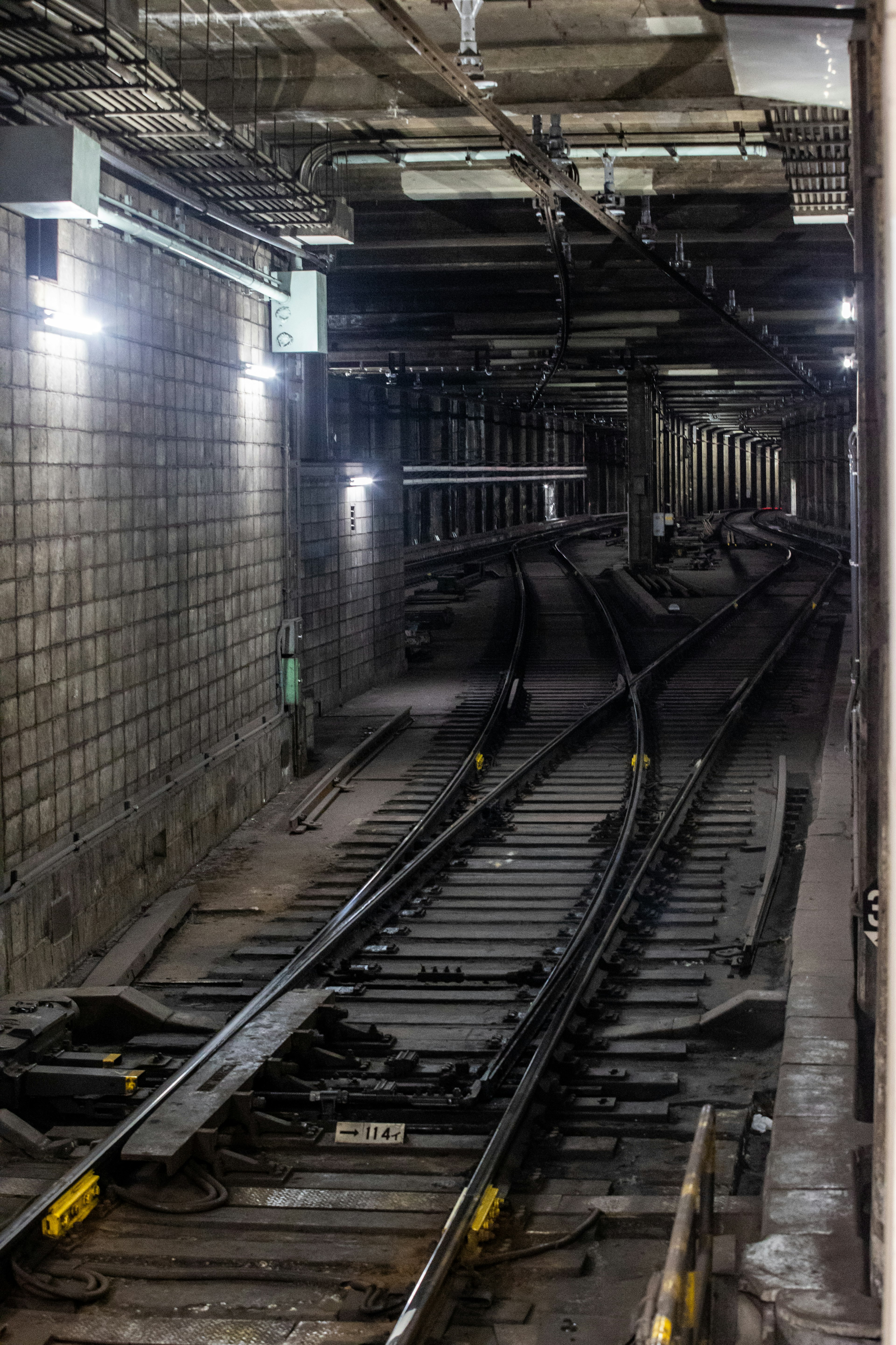 Interior de un túnel de metro con rieles iluminados que se curvan en la distancia