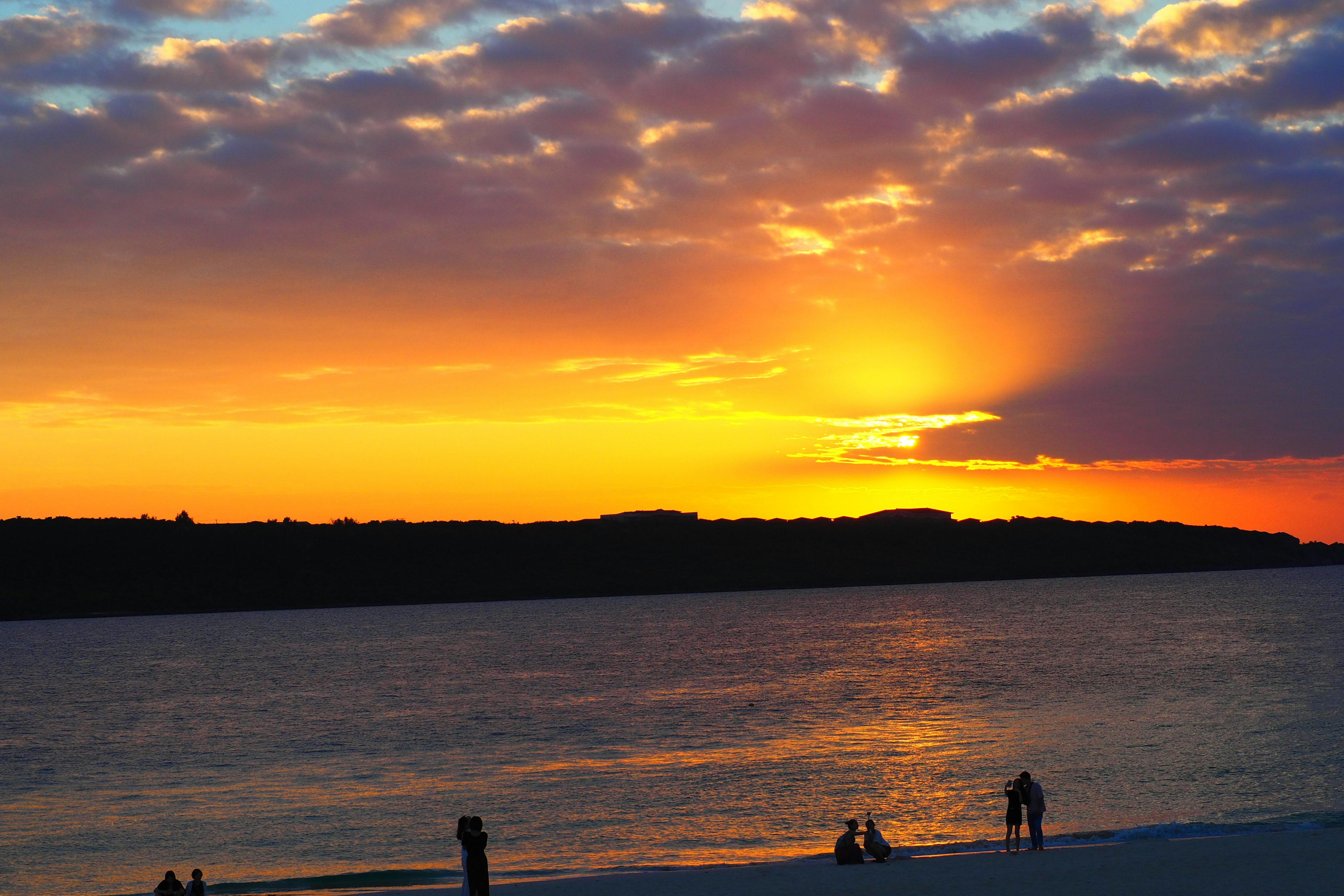 Coastal sunset scene with silhouettes of people