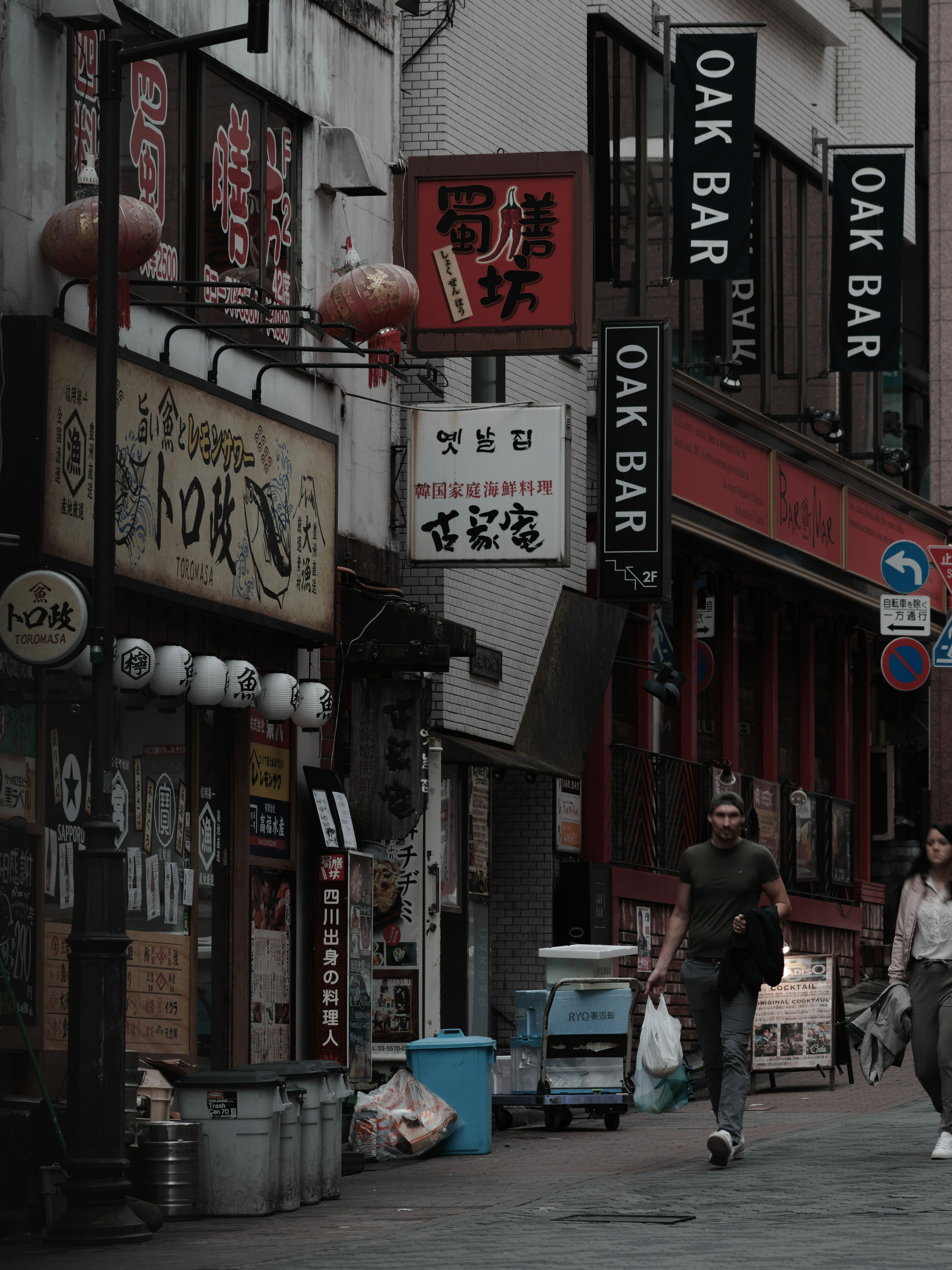 Narrow street with restaurants and shop signs in muted colors